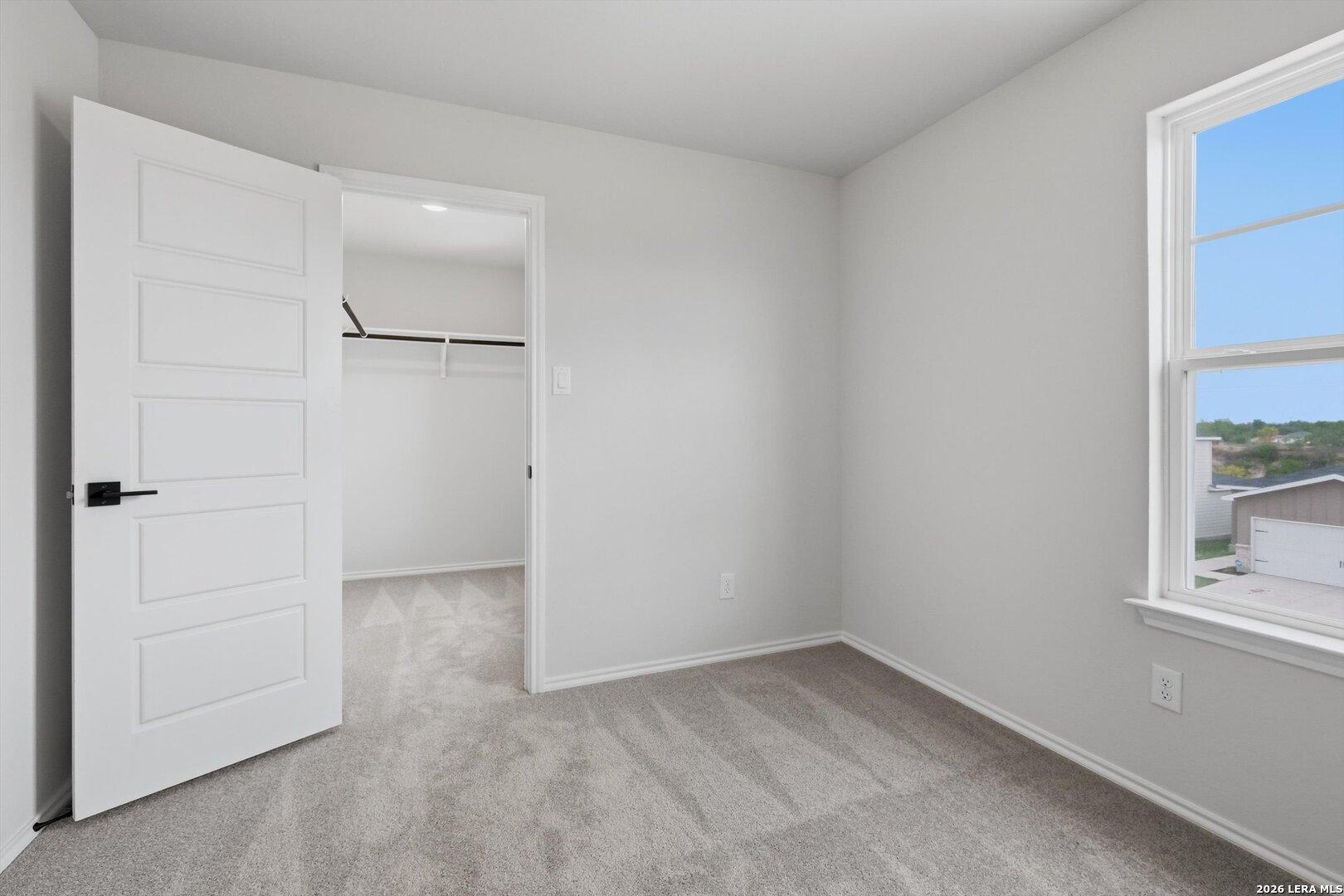 Bright secondary bedroom with open closet, gray carpet, and window view in Davidson Homes The Blanco C, Agave, San Antonio
