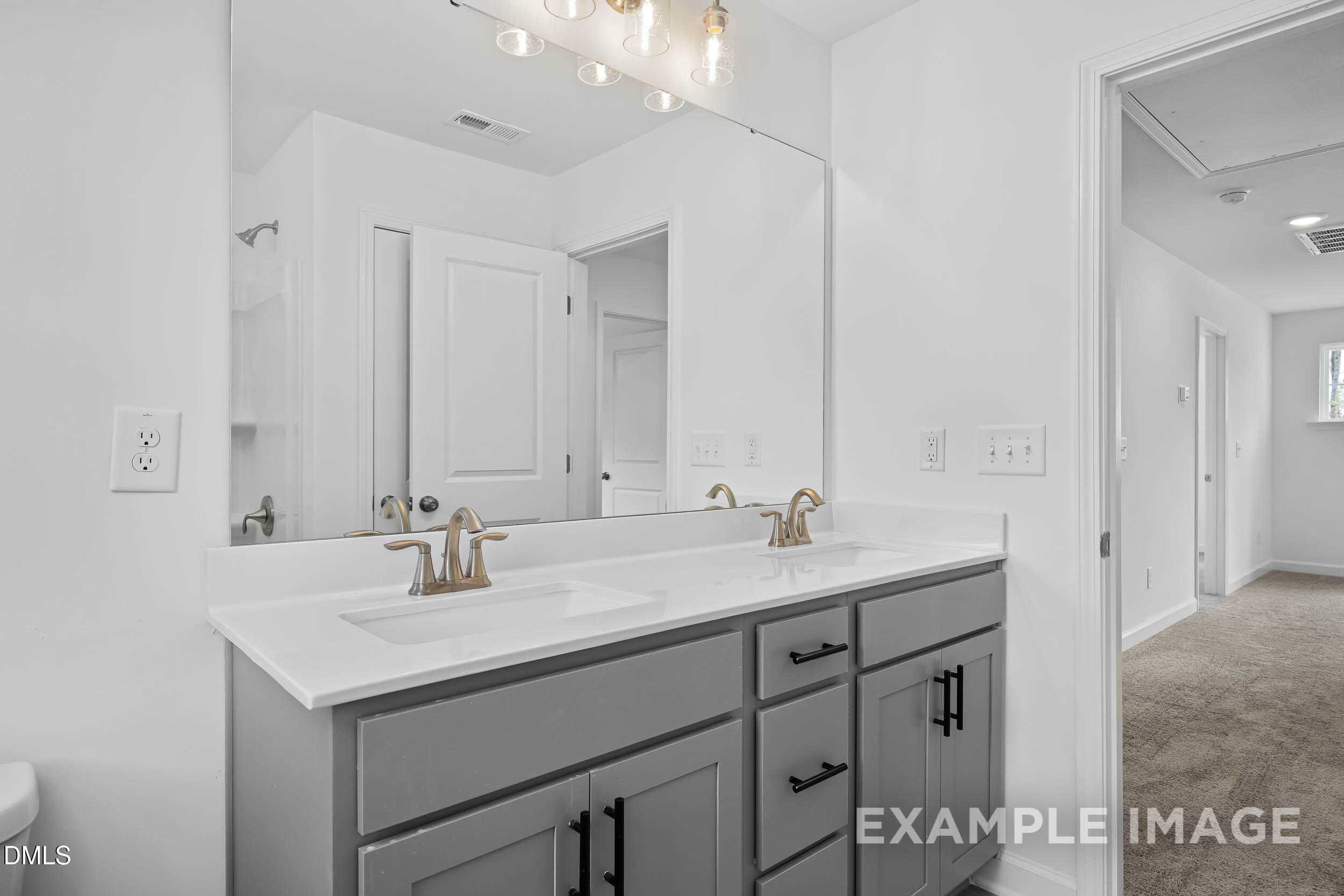 Modern double vanity in master bathroom with gray cabinets, white quartz counters, gold faucets in The Willow D, Zebulon, NC