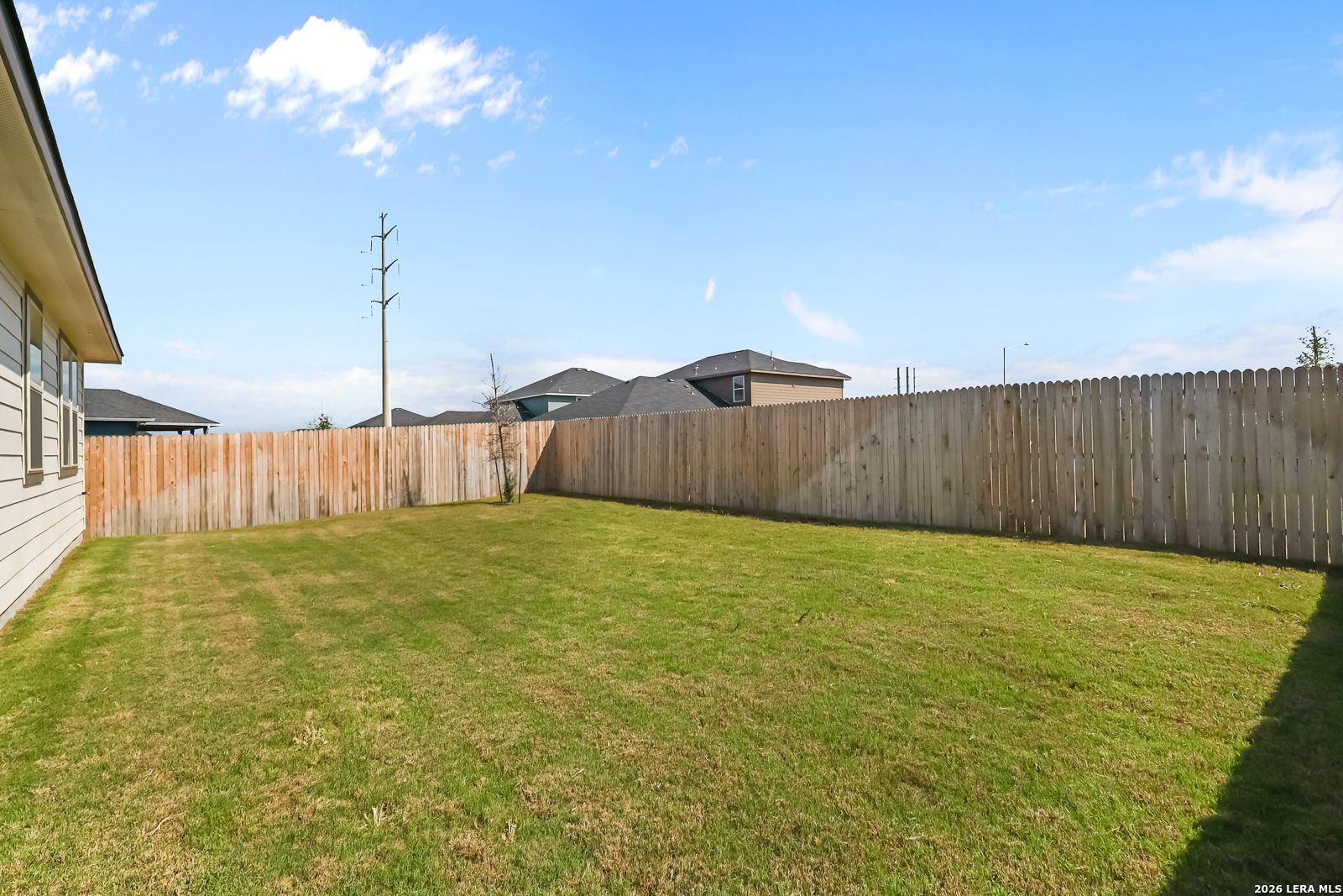 Expansive private backyard with lush green lawn and wooden privacy fence in Davidson Homes The Daphne H, Hannah Heights, Seguin, Texas