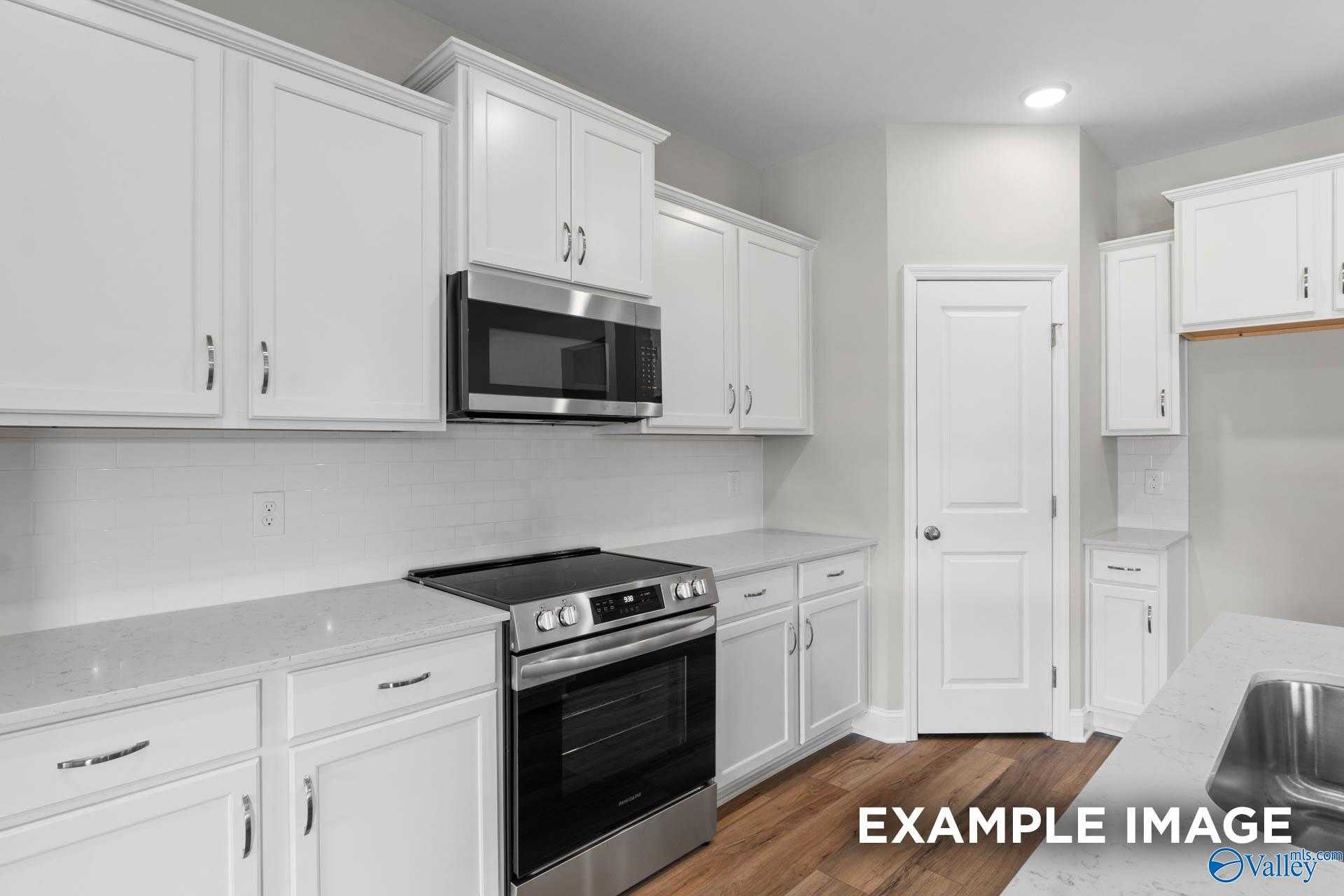 Modern kitchen featuring white shaker cabinets, stainless steel oven and cooktop, quartz counters in Davidson Homes The Everett, Meridianville, AL