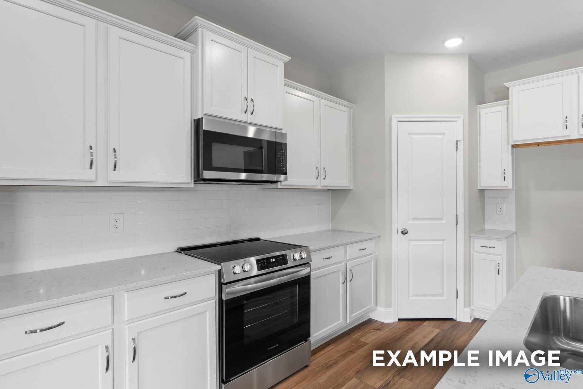 Modern kitchen featuring white shaker cabinets, stainless steel oven and cooktop, quartz counters in Davidson Homes The Everett, Meridianville, AL