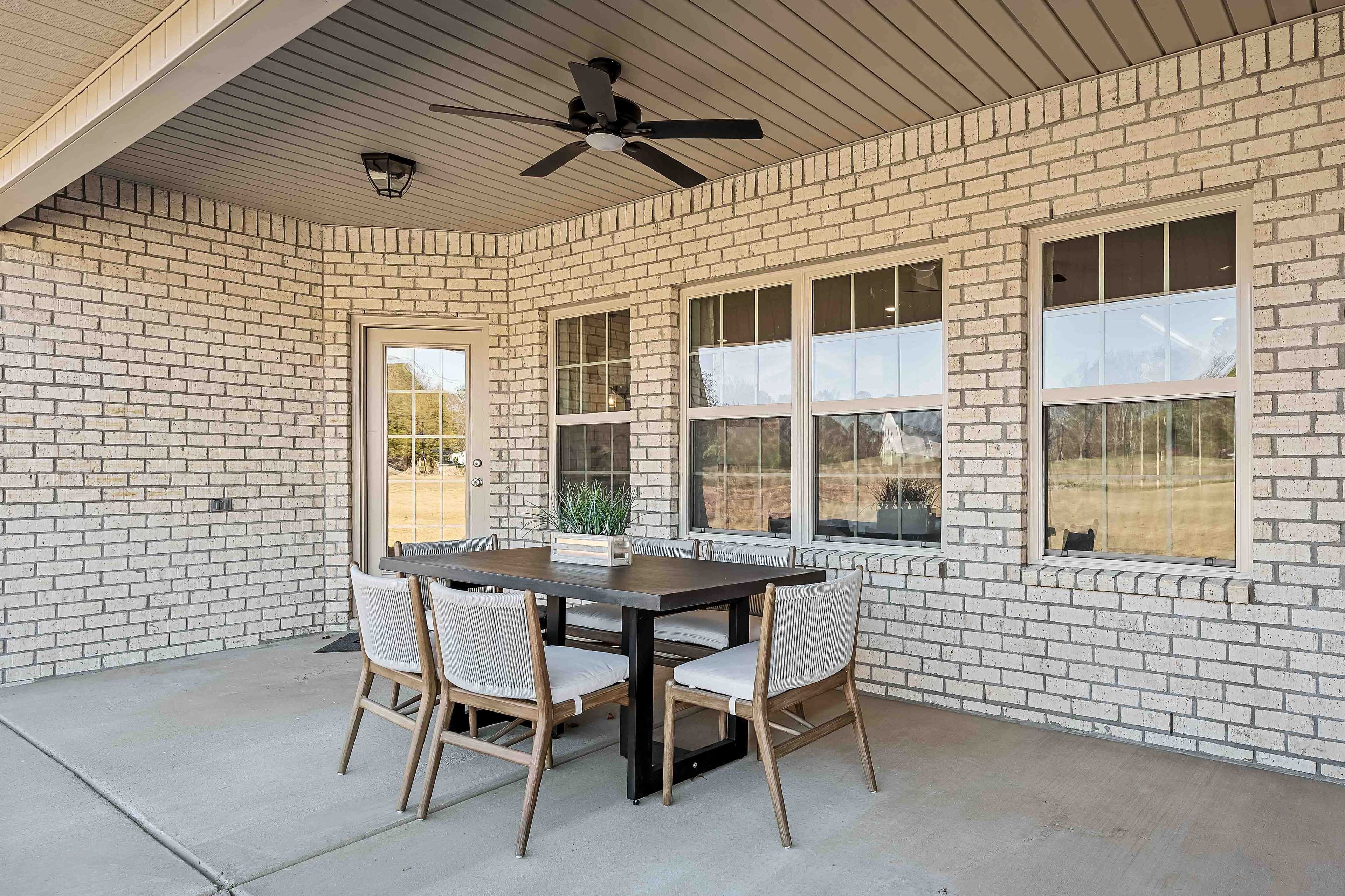 Spacious covered patio at Cain Park in Hartselle Alabama with white brick walls ceiling fans and wicker dining set