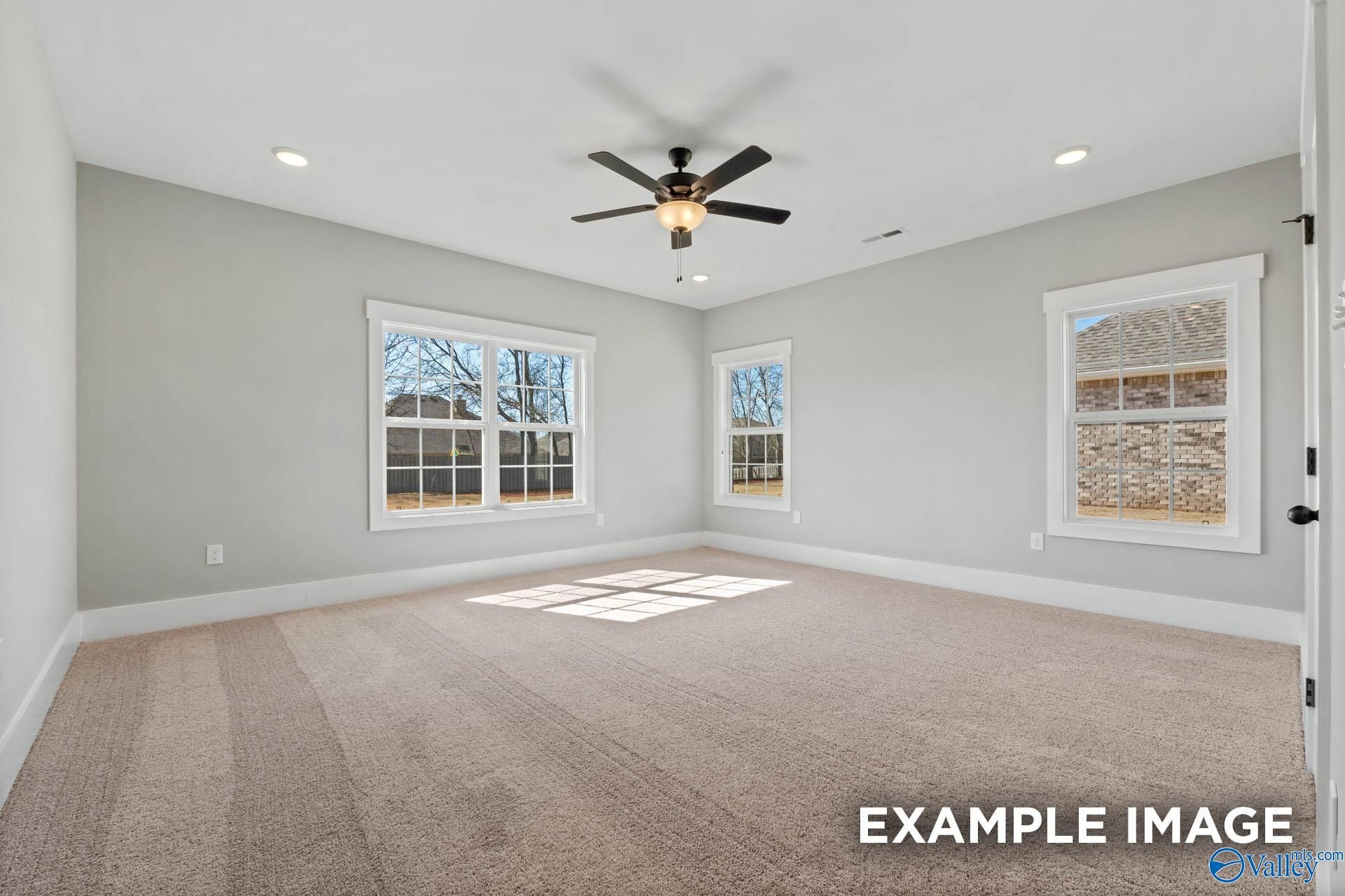 Spacious, sunlit bedroom with neutral carpet and ceiling fan in The Finleigh floor plan by Davidson Homes in Meridianville.