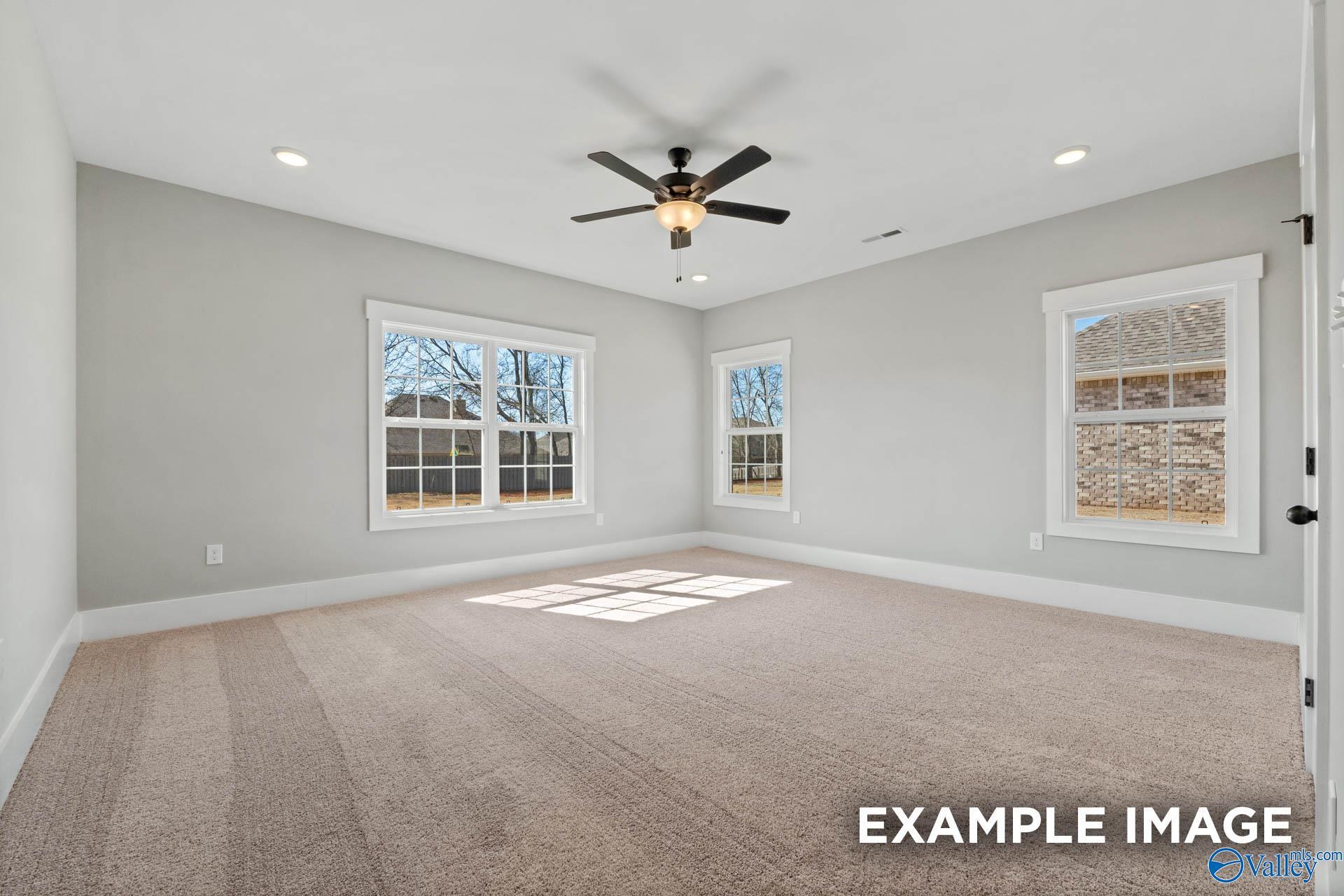 Spacious, sunlit bedroom with neutral carpet and ceiling fan in The Finleigh floor plan by Davidson Homes in Meridianville.