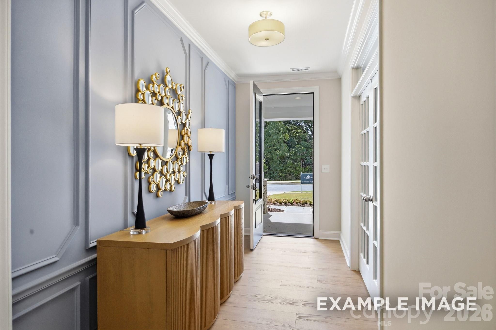 Elegant foyer with blue wainscoting and gold mirror in The Hickory B II floor plan by Davidson Homes in Windgate, NC.