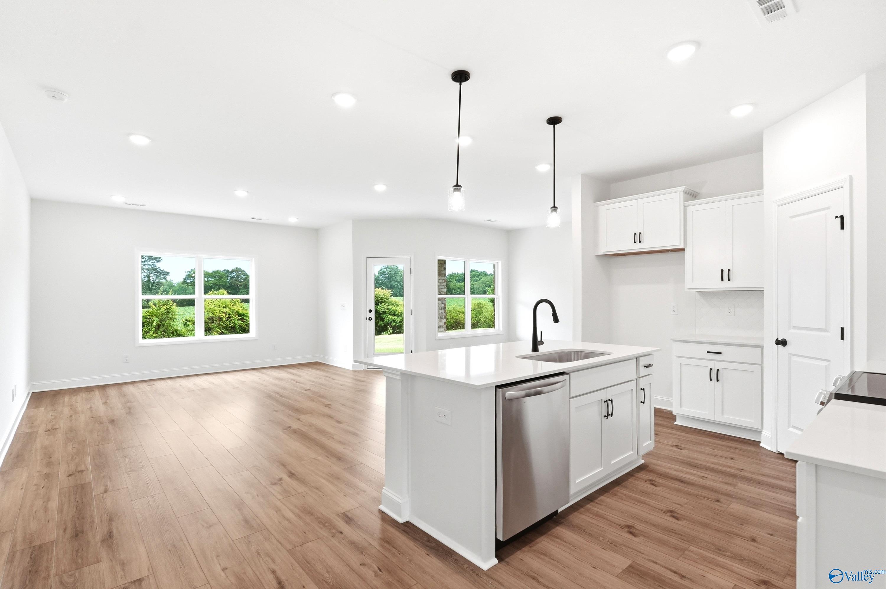 Open-concept kitchen with white cabinets and quartz island in The Daphne C floor plan by Davidson Homes in Toney, Alabama.