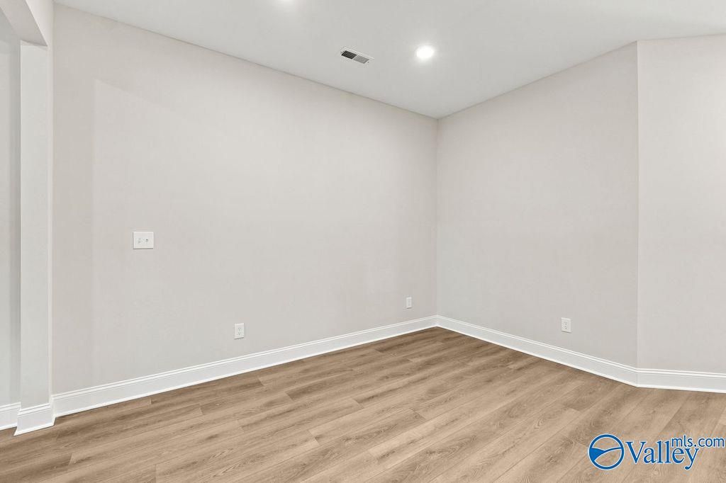 Bright, open-concept flex room with neutral paint and wood-style flooring in The Camilla C home at The Retreat, Hartselle.