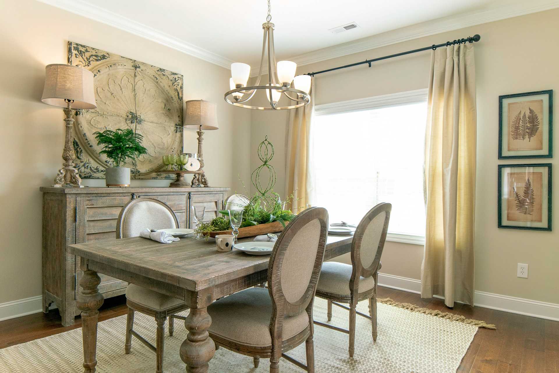 Elegant dining room at The Dairy at Oak Grove in South Huntsville AL with rustic wooden table, chandelier, and sheer curtains