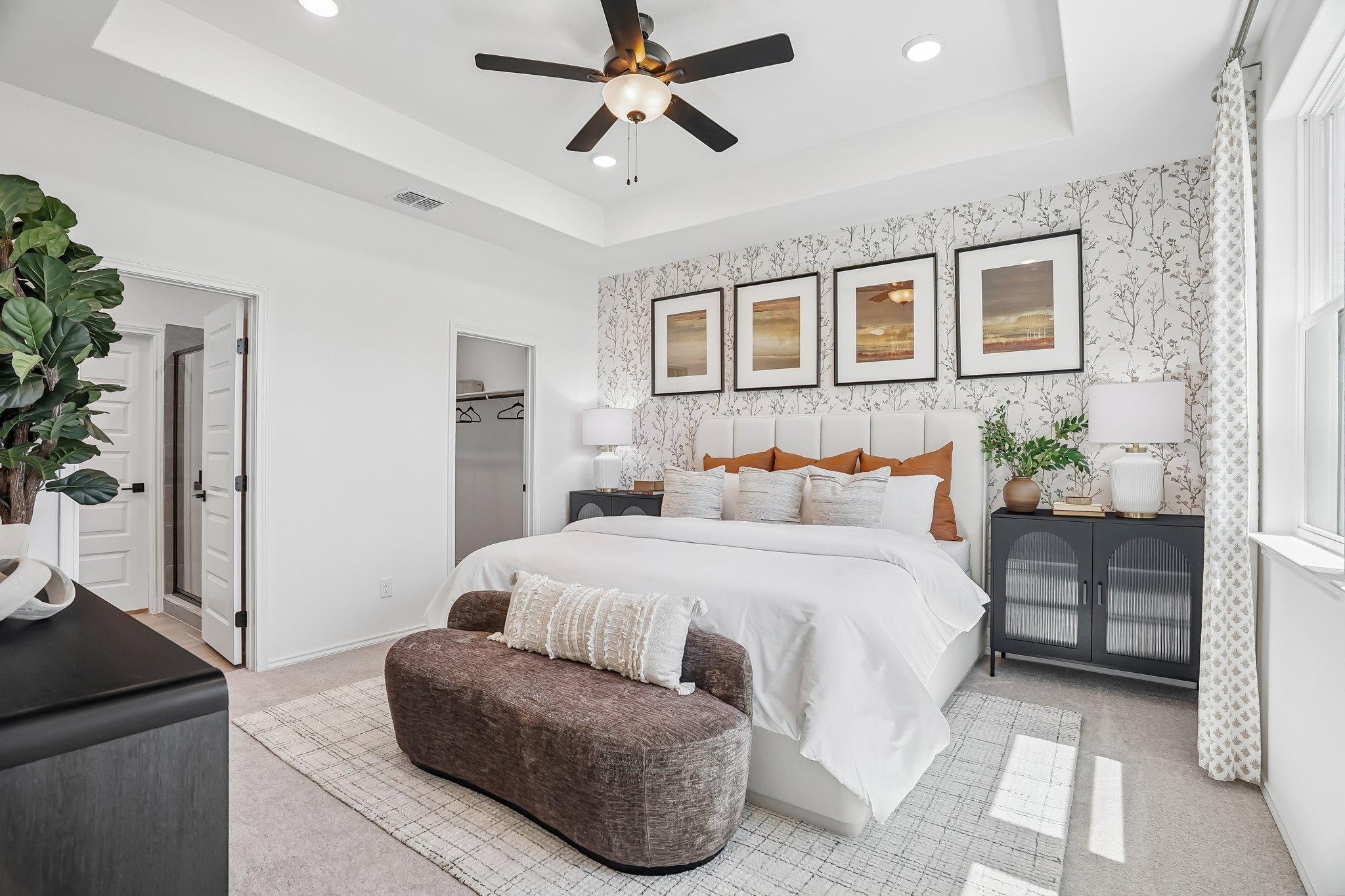 Spacious primary bedroom at Fairway Crossing in Converse, TX by Davidson Homes with tray ceiling and patterned accent wall.