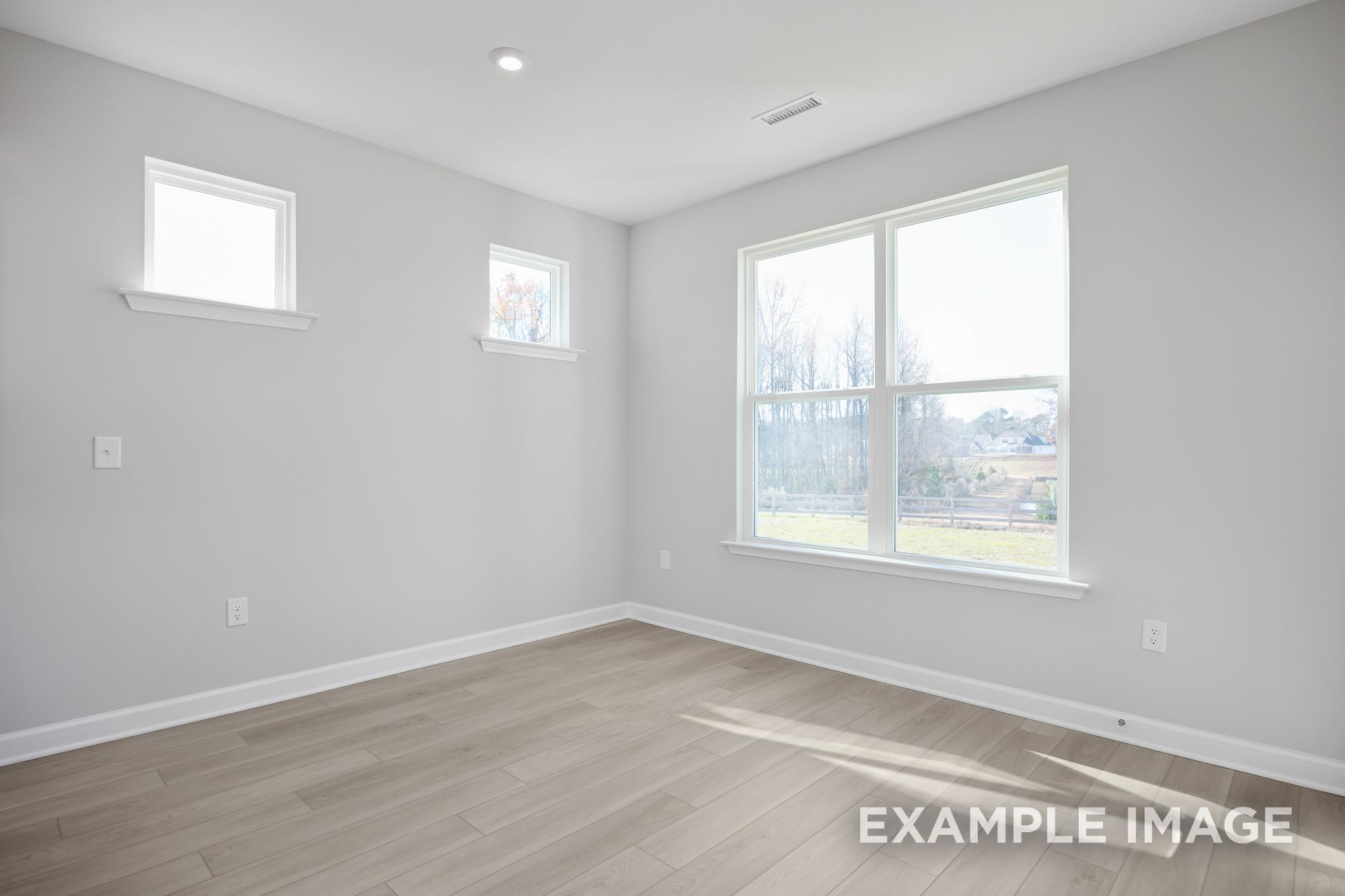 Bright upper-floor master suite in The Cypress C II, Davidson Homes design, featuring large windows, gray walls, hardwood floors, Angier NC