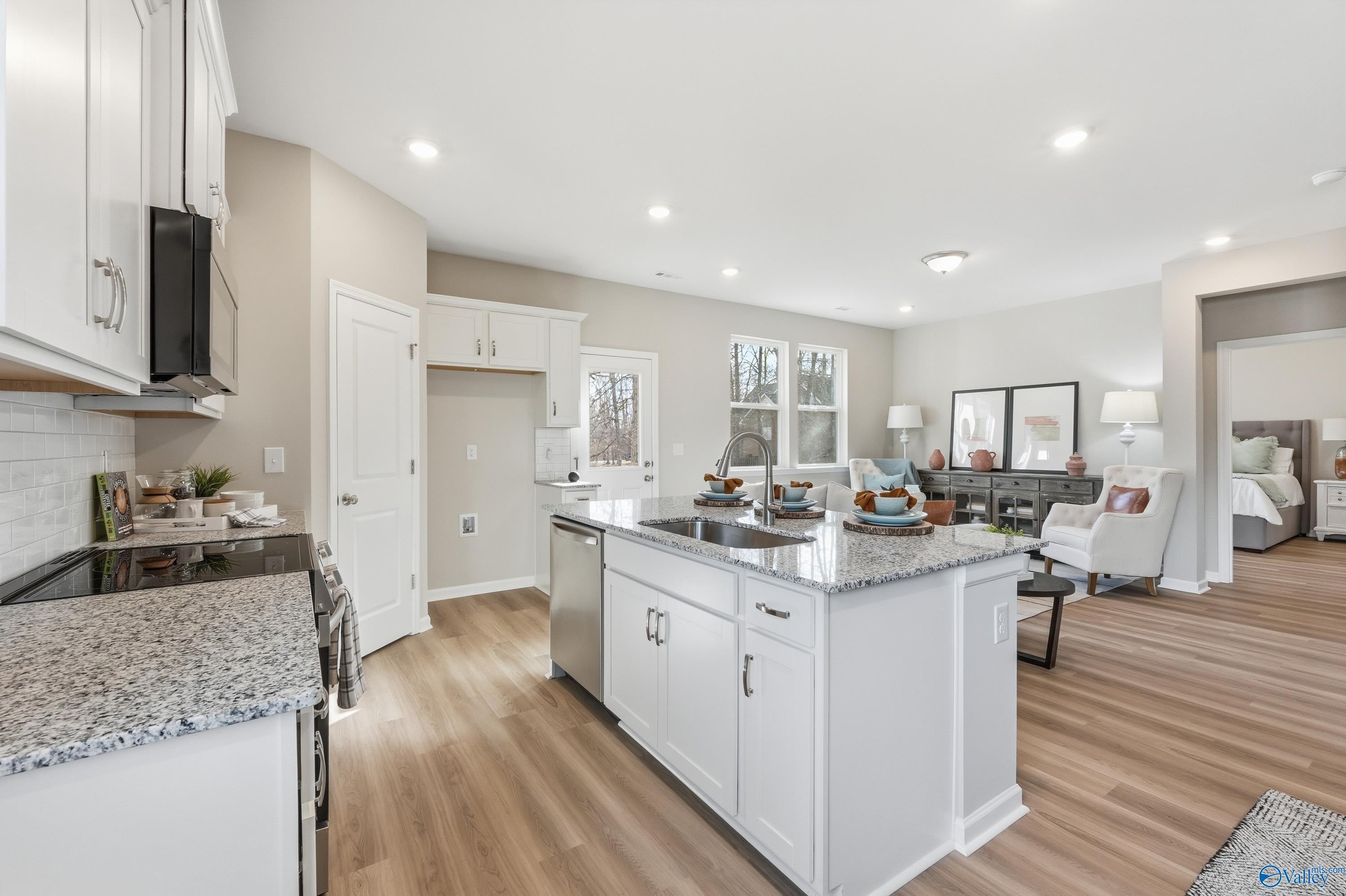 Modern open-concept kitchen featuring white shaker cabinets, granite island, stainless appliances in Davidson Homes The Polaris, Fayetteville, TN