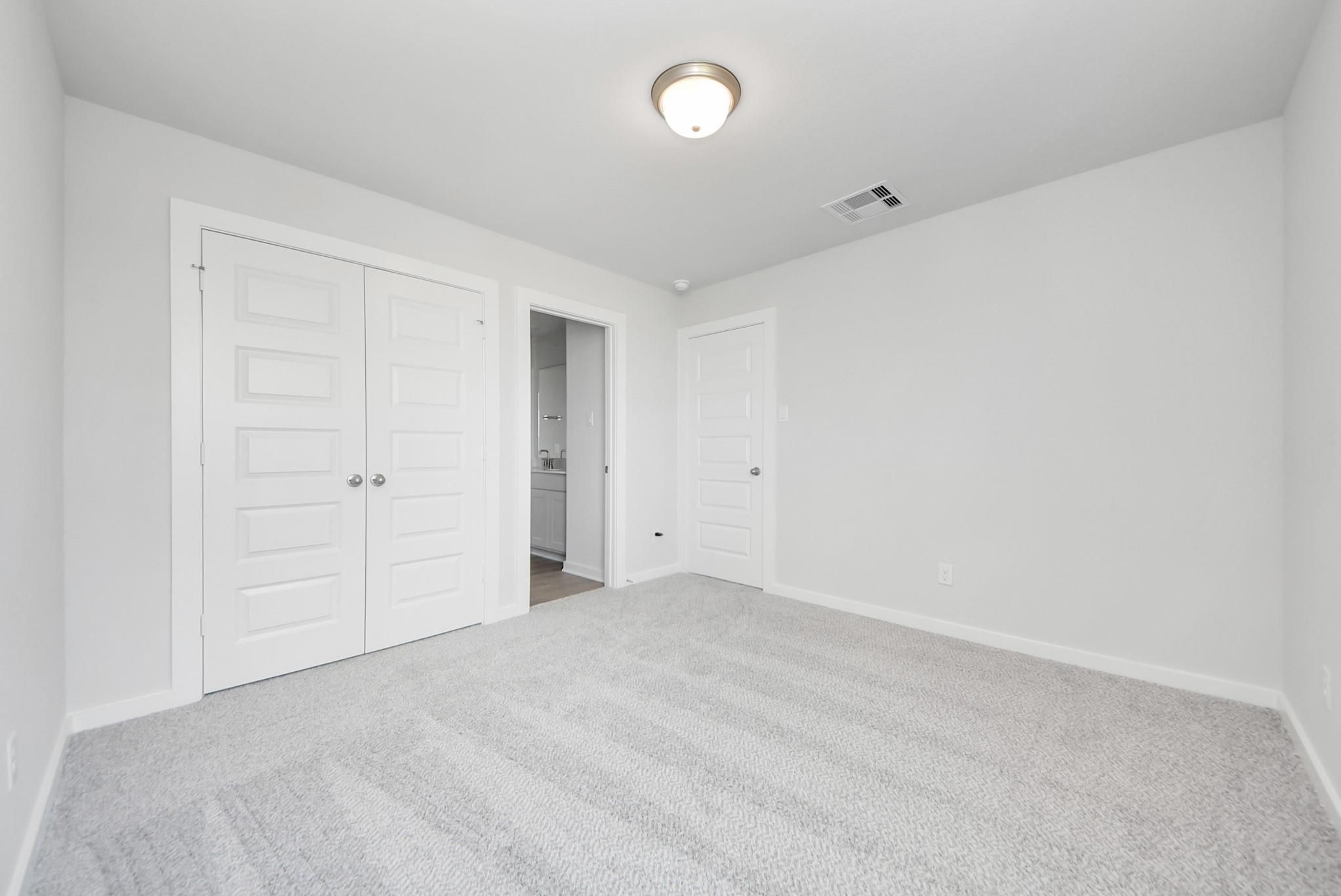 Bright secondary bedroom with plush carpet and closet space in The Verano B floor plan by Davidson Homes in Sunterra, Katy.