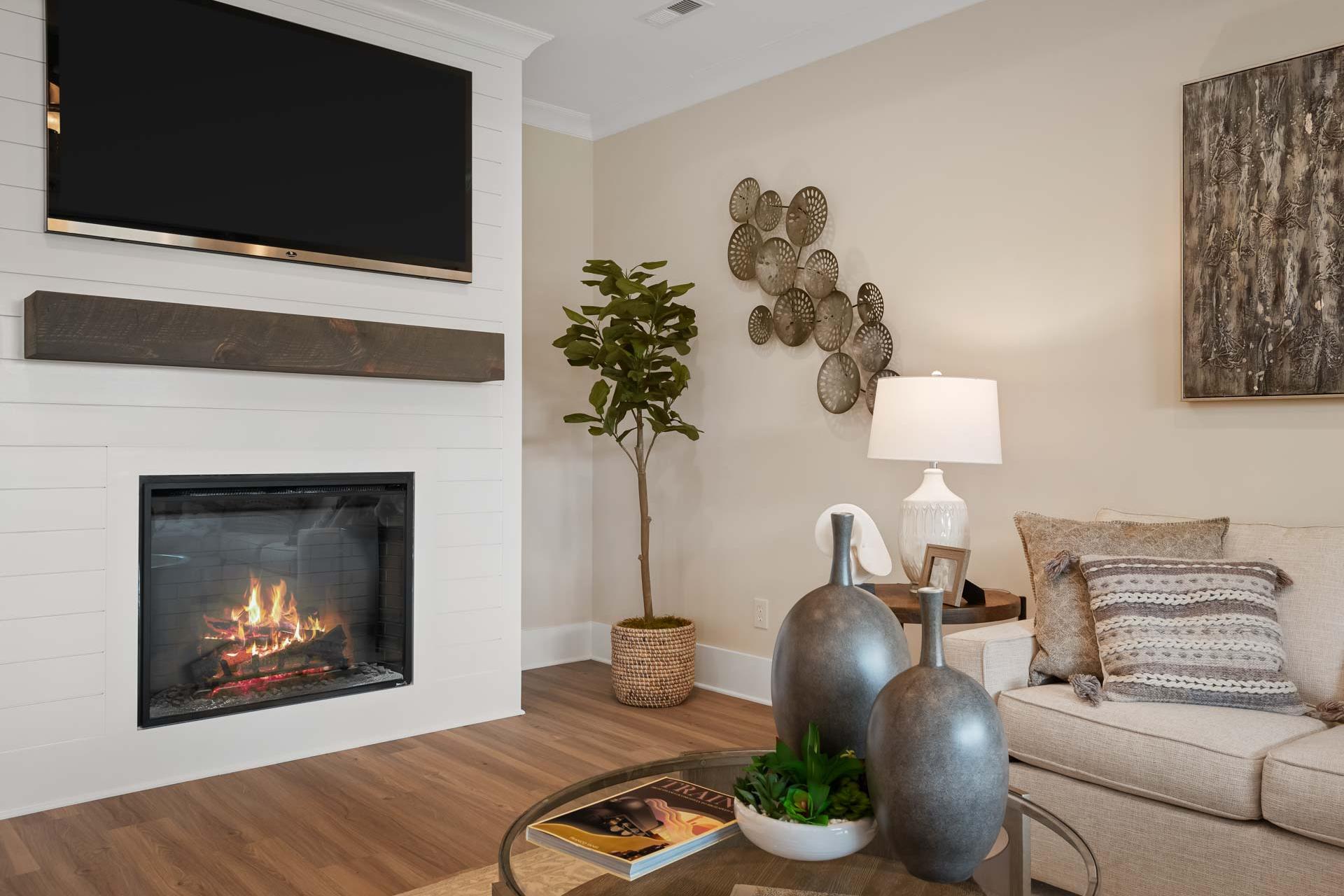 Cozy living room at Flint Meadows in New Market, Alabama with gas fireplace, mounted TV, hardwood floors and neutral decor