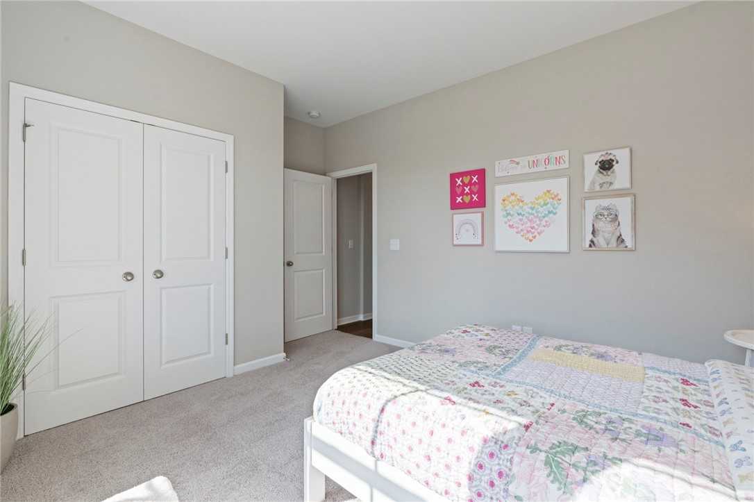 Cozy girl's bedroom with floral pink bedding, colorful wall art, walk-in closet in Davidson Homes The Phoenix B, Opelika, Alabama