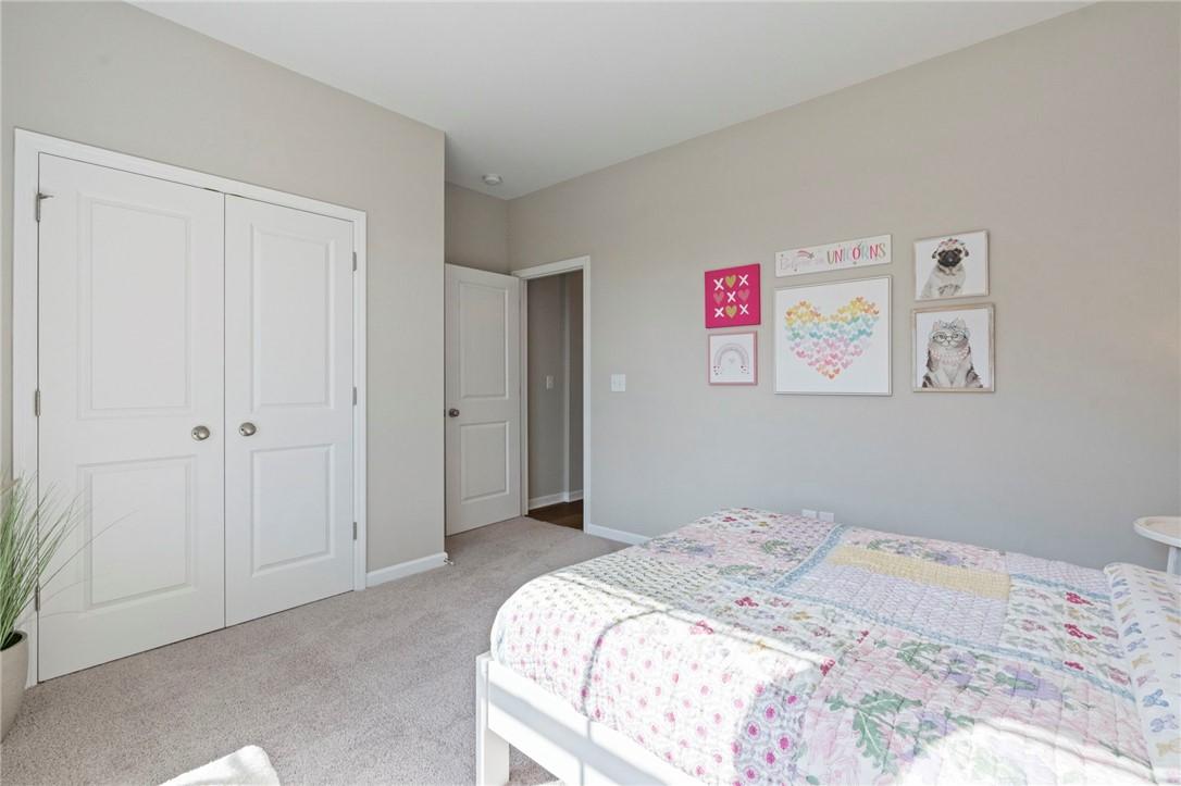Charming girl's bedroom with floral bedspread, pink wall art, and white closet doors in Davidson Homes The Phoenix B, Opelika, Alabama