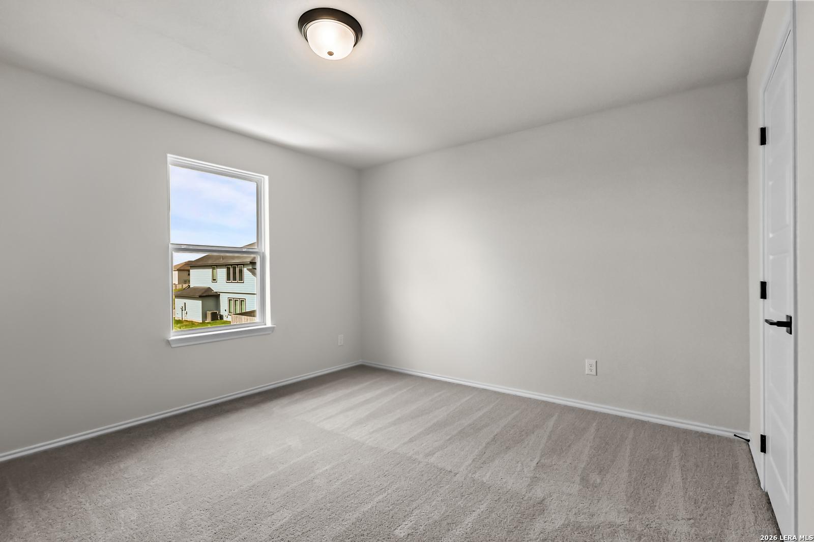 Bright bedroom with neutral walls and plush carpet in The Douglas C floor plan at Hannah Heights, Seguin, Texas.