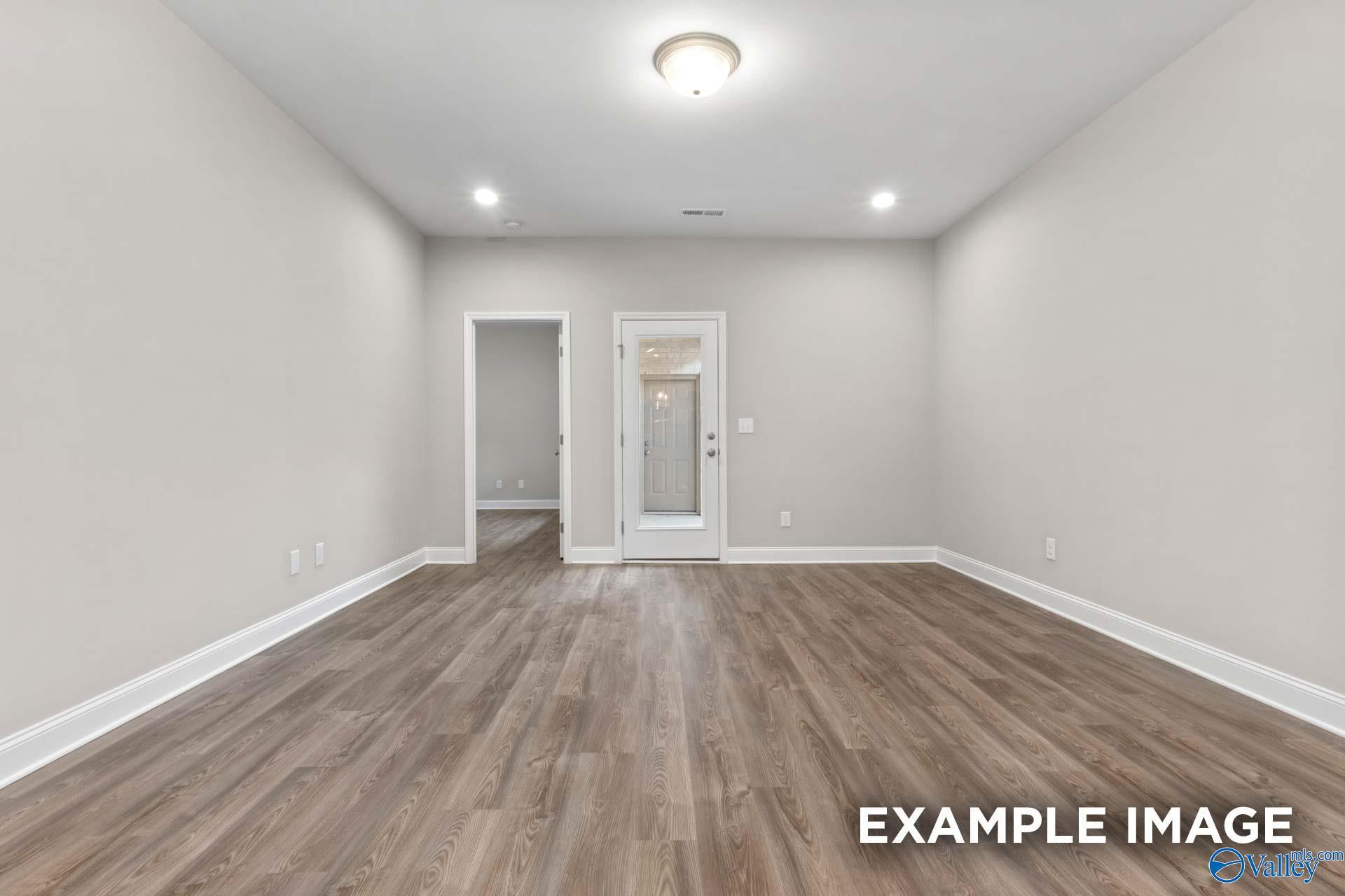 Bright living area with wood-look flooring and glass door in The Camilla A floor plan at The Retreat at Cain Park.