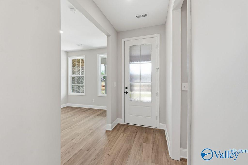 Bright entryway with frosted glass door, hardwood floors, and light gray walls in Davidson Homes The Rockford, Cain Park Hartselle AL