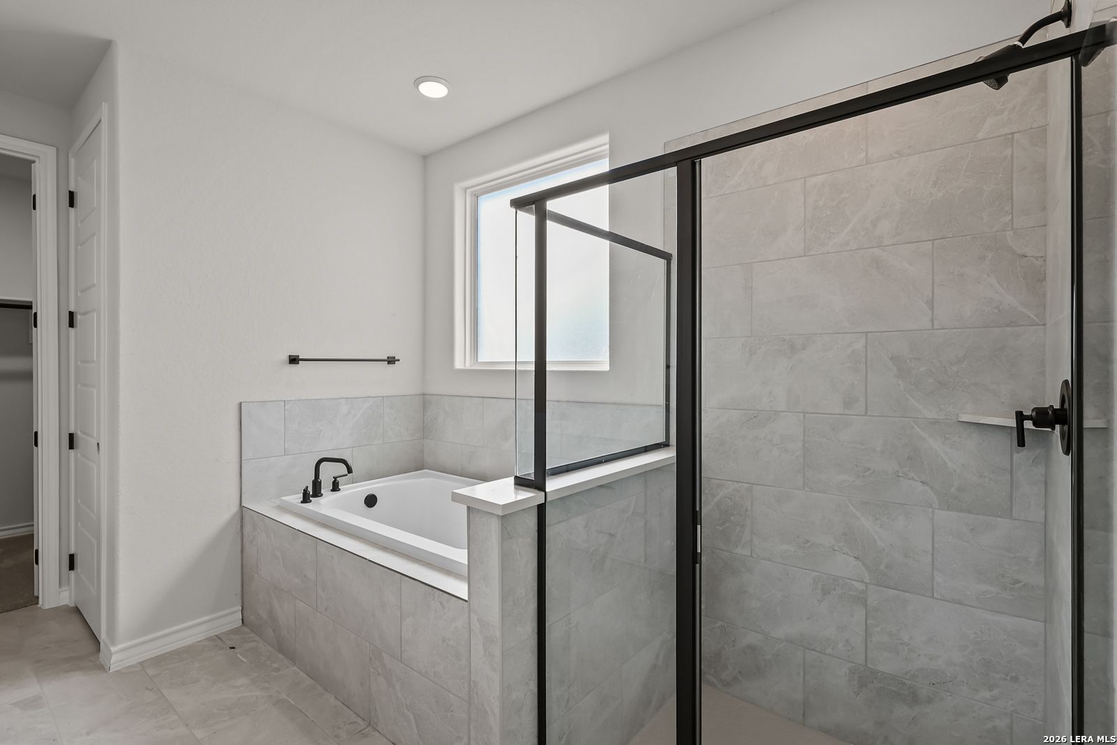 Modern master bathroom with soaking tub, glass walk-in shower, and gray tile in Davidson Homes Oxford F, Castroville, Texas