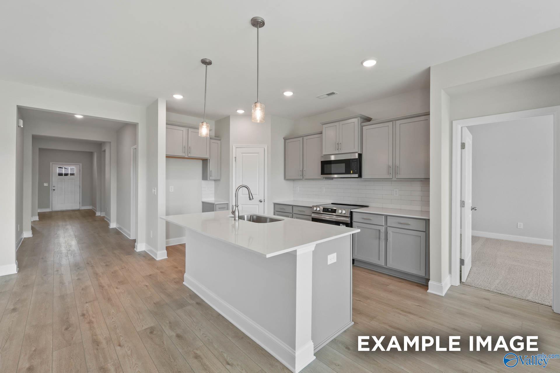Modern kitchen with gray cabinets and white quartz island in The Everett B floor plan, The Meadows, Athens, Alabama.