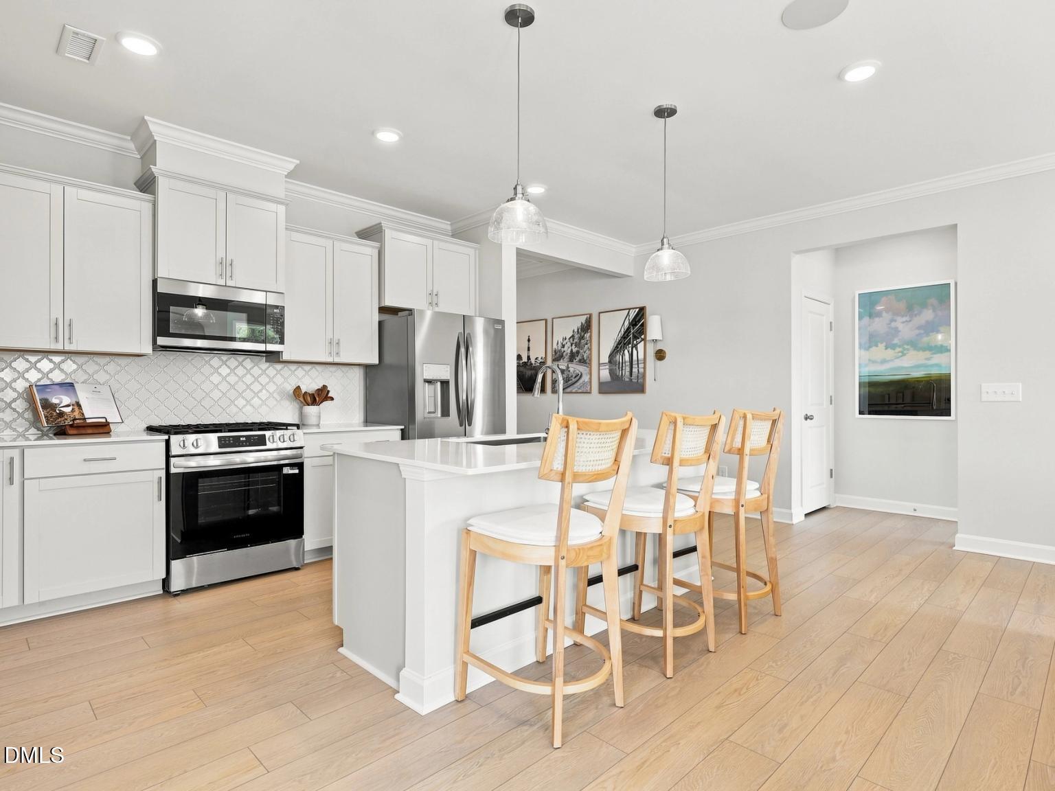 Modern kitchen with white cabinets, quartz island, and bar seating in The Daphne C floor plan at Woodland Crossing, Zebulon.