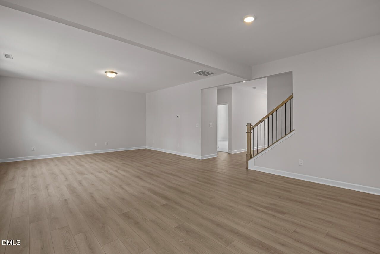 Spacious open-concept living area with wood-style flooring in The Hickory II B floor plan at Wellers Knoll, Lillington, NC.