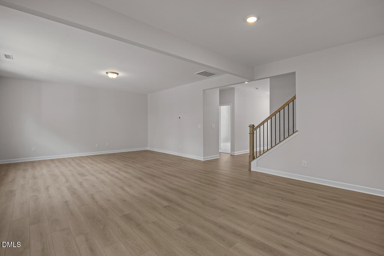 Spacious open-concept living area with wood-style flooring in The Hickory II B floor plan at Wellers Knoll, Lillington, NC.
