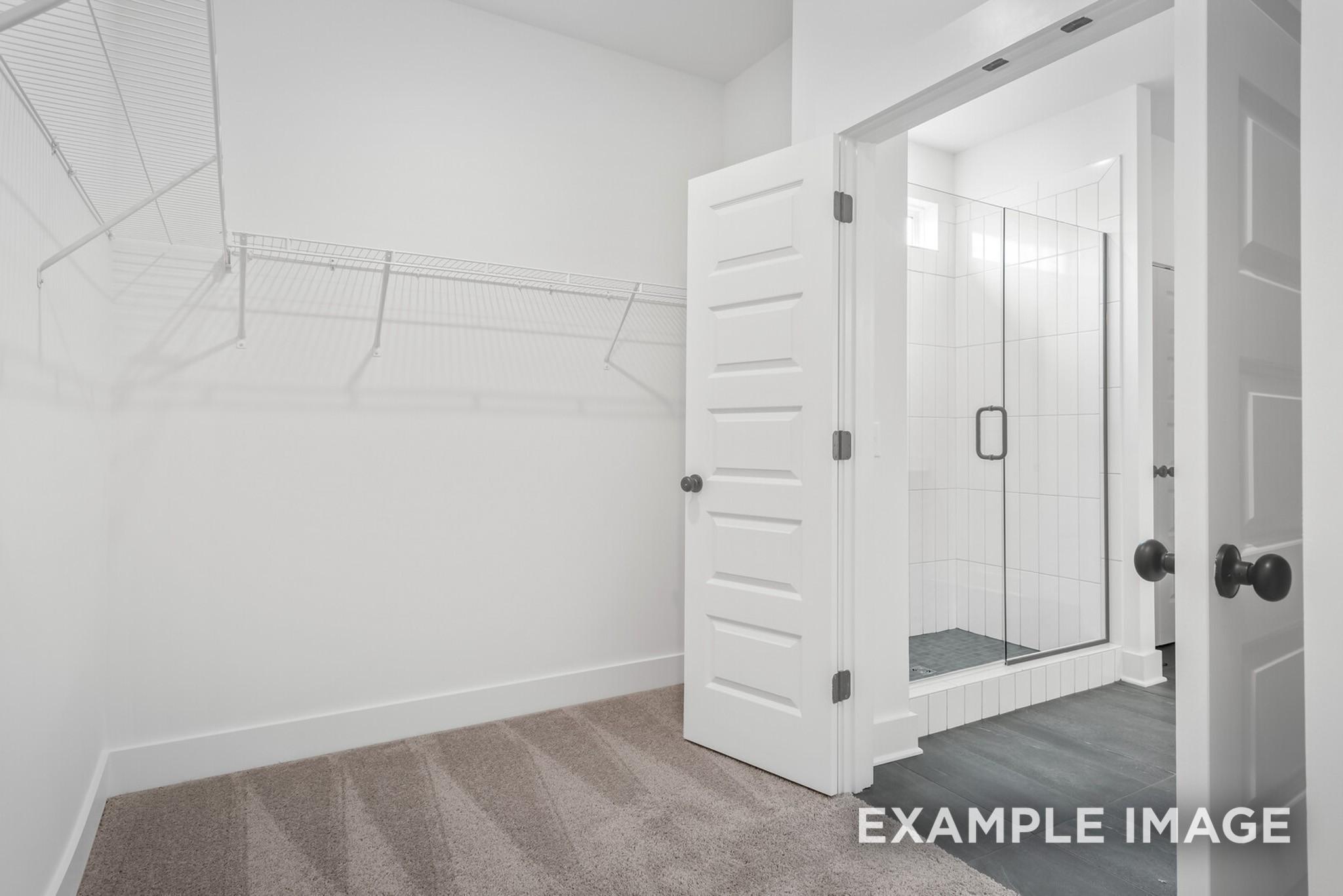 Spacious walk-in closet with wire shelving adjacent to frameless glass shower in master bath of Davidson Homes The Ridgeport C, Gallatin, TN