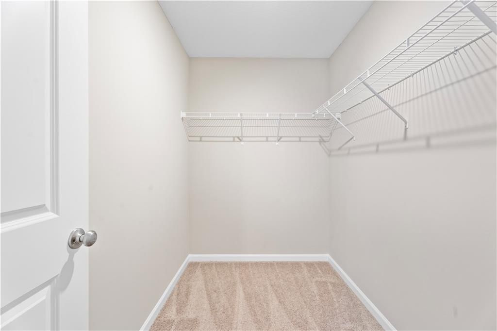 Spacious walk-in closet with white wire shelving and beige walls in Davidson Homes The Washington, Phenix City, Alabama