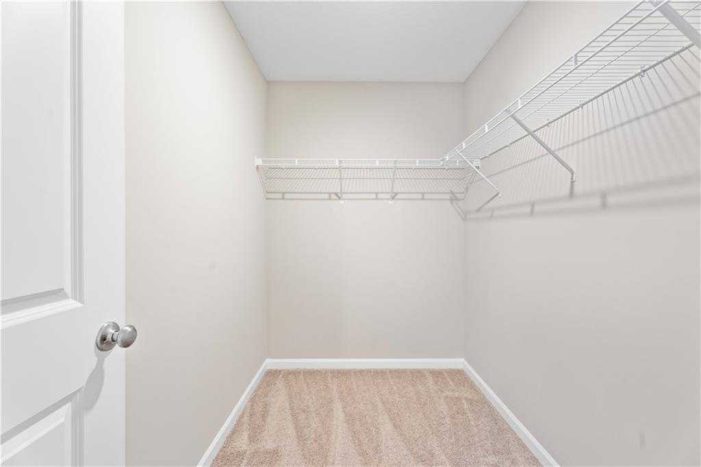 Spacious walk-in closet with white wire shelving and beige walls in Davidson Homes The Washington, Phenix City, Alabama