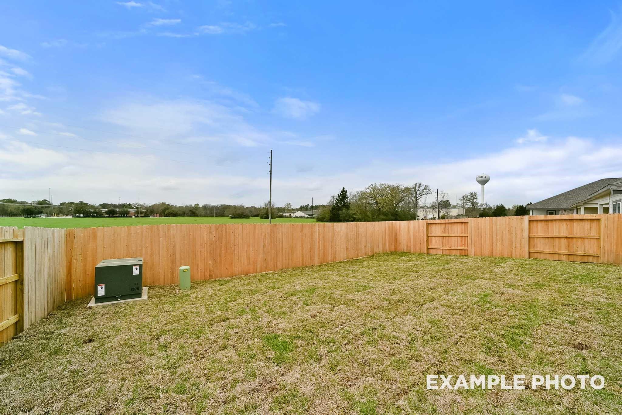 Spacious private backyard with wooden fence, green lawn, and utility area in Davidson Homes The Tierra B, Emberly, Beasley, Texas