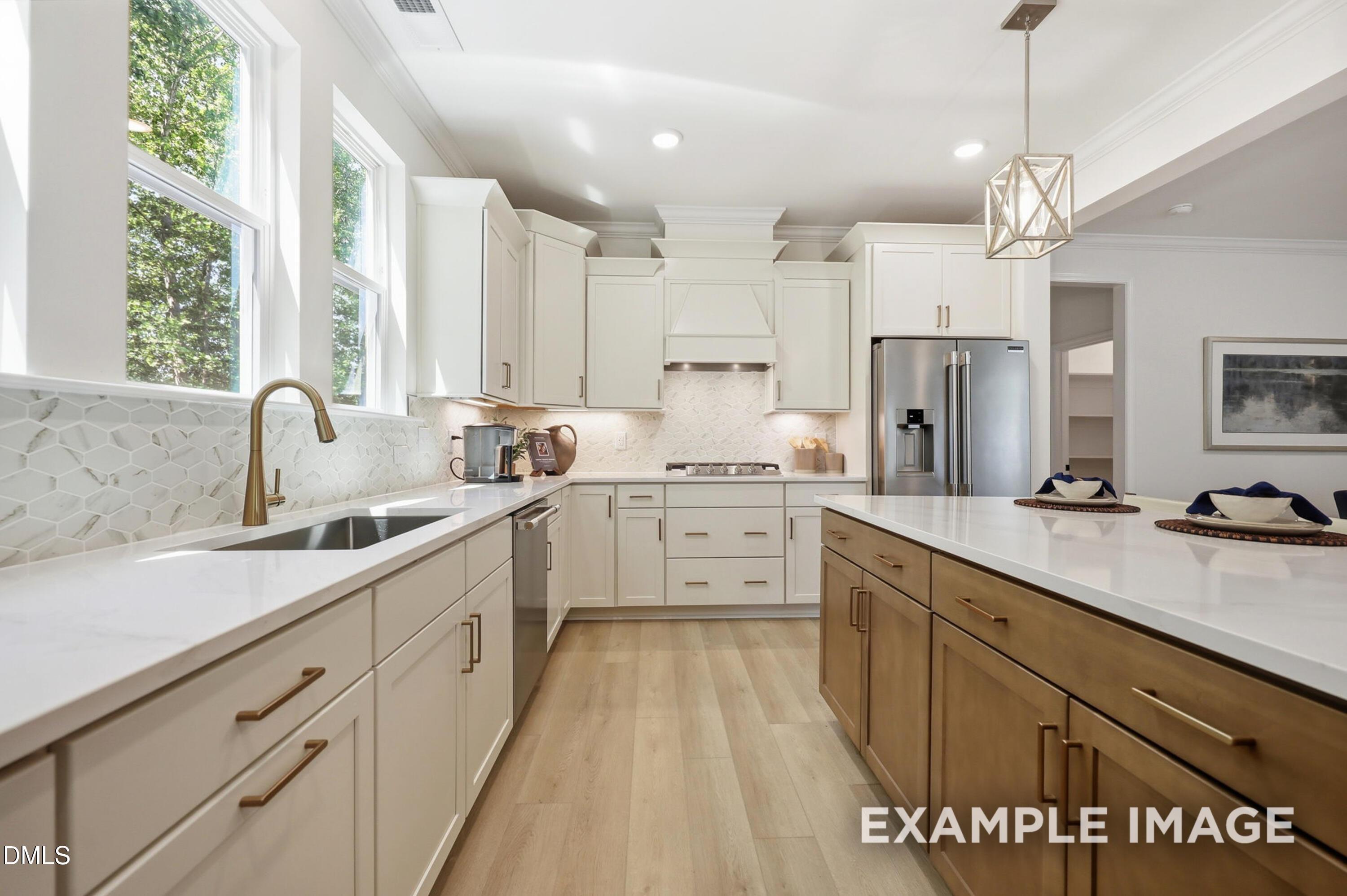 Modern kitchen with white cabinets, wood island, and brass hardware in The Aspen B floor plan at Wendell Ridge, NC.