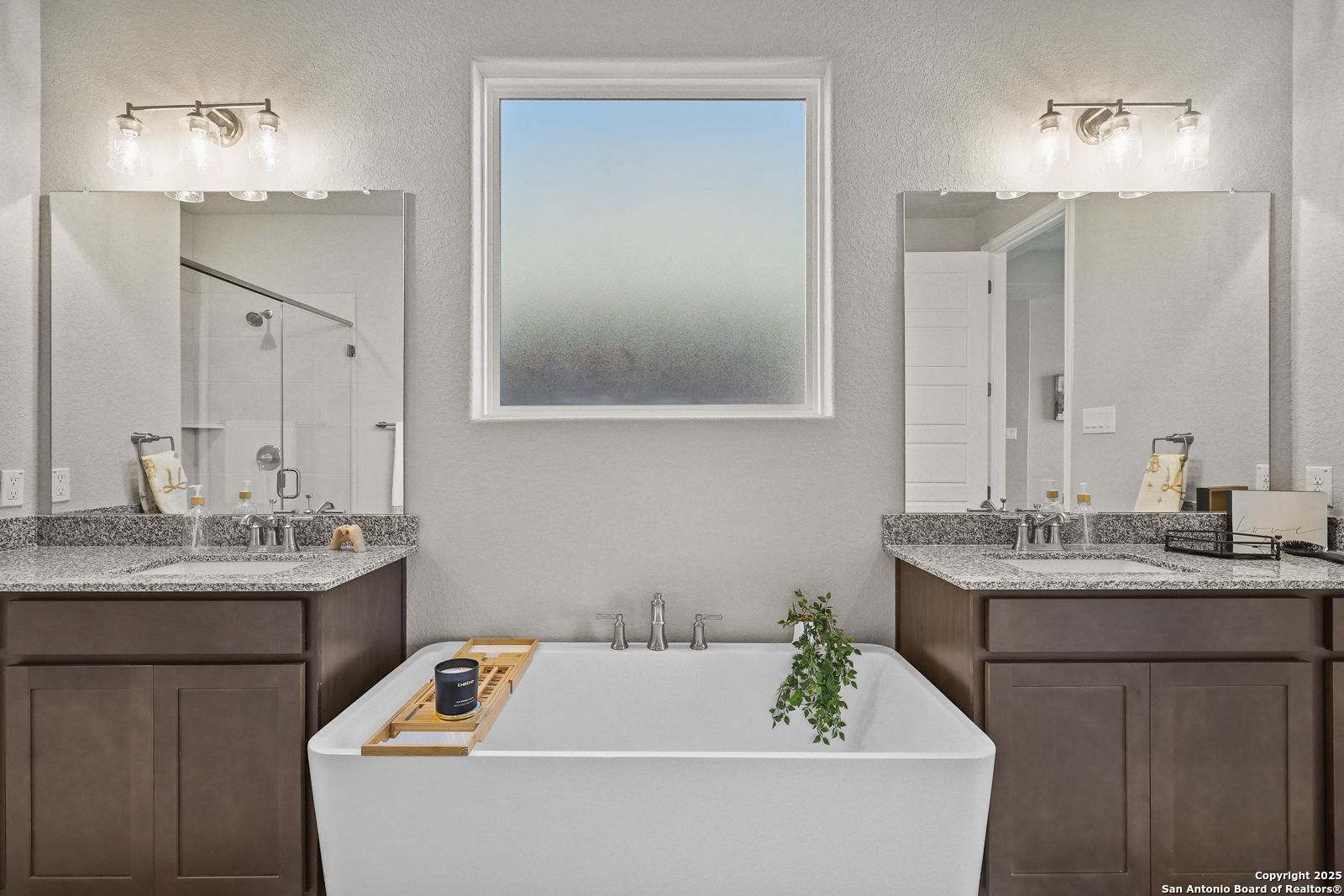 Elegant master bath with freestanding tub, double vanity, mirrors, and frosted window in Davidson Homes The Jennings G, Castroville, TX