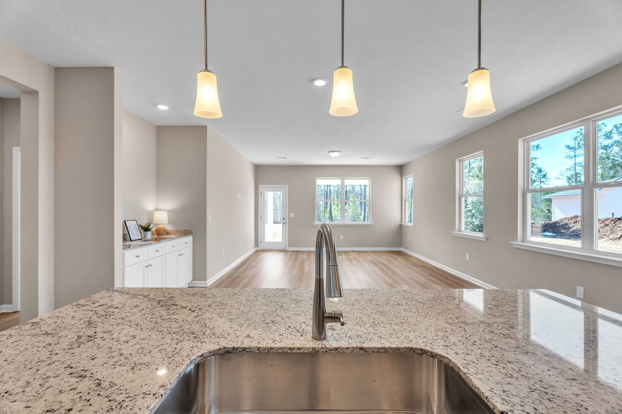 Spacious open-concept kitchen with granite countertops, stainless sink, and pendant lights at Anderson Lakes in Opelika AL