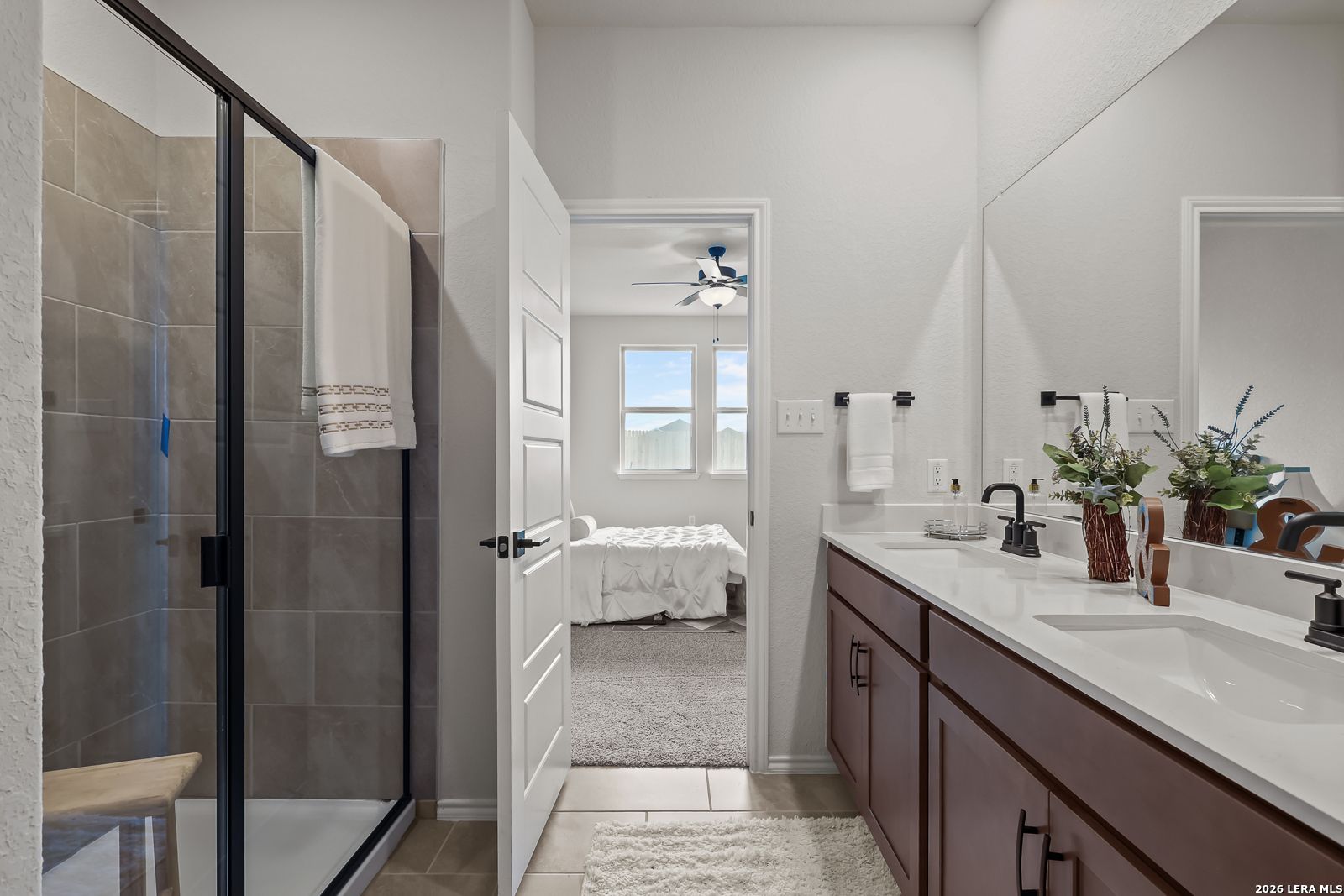 Elegant master bathroom with frameless glass shower, double vanity, and open view to bedroom in Davidson Homes The Daphne H, Seguin, Texas
