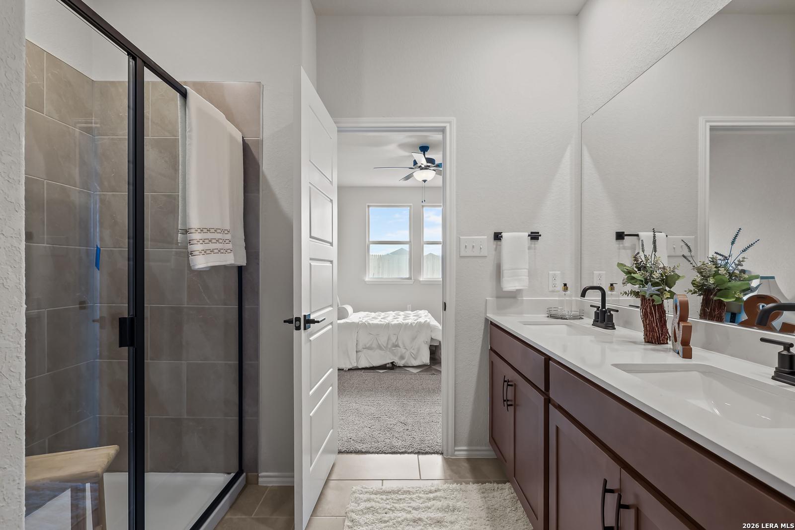 Elegant master bathroom with frameless glass shower, double vanity, and open view to bedroom in Davidson Homes The Daphne H, Seguin, Texas