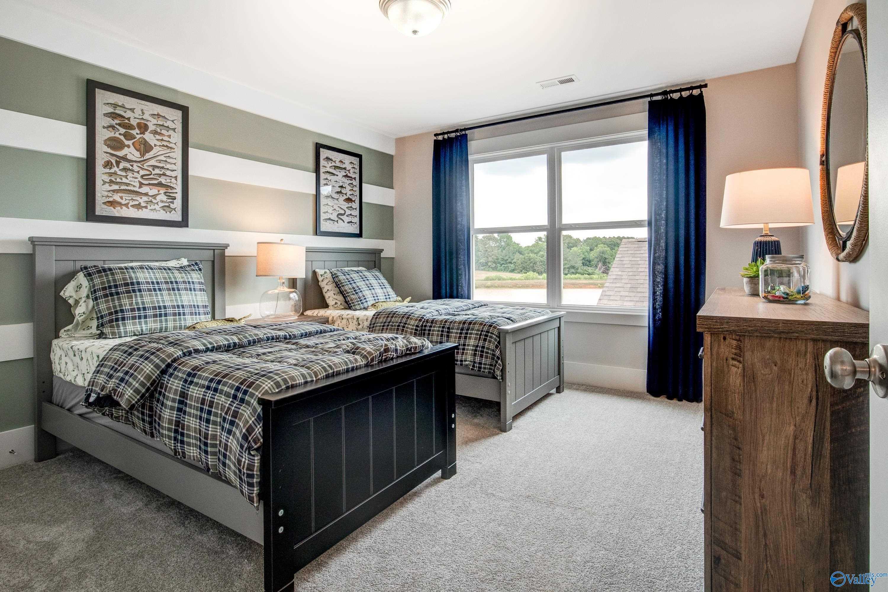 Cozy twin bedroom with plaid bedding, striped walls, and window view in Davidson Homes The Covington C, Decatur, Alabama