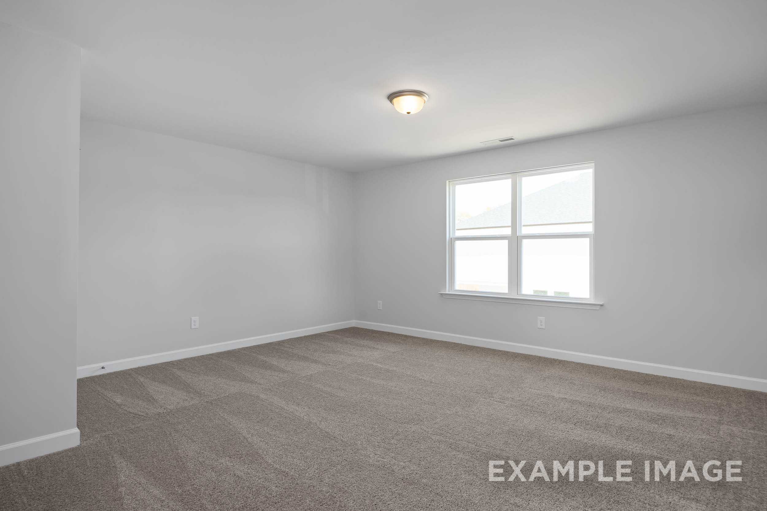 Spacious empty bedroom in The Ash Davidson Homes design with gray walls, beige carpet, and large double windows