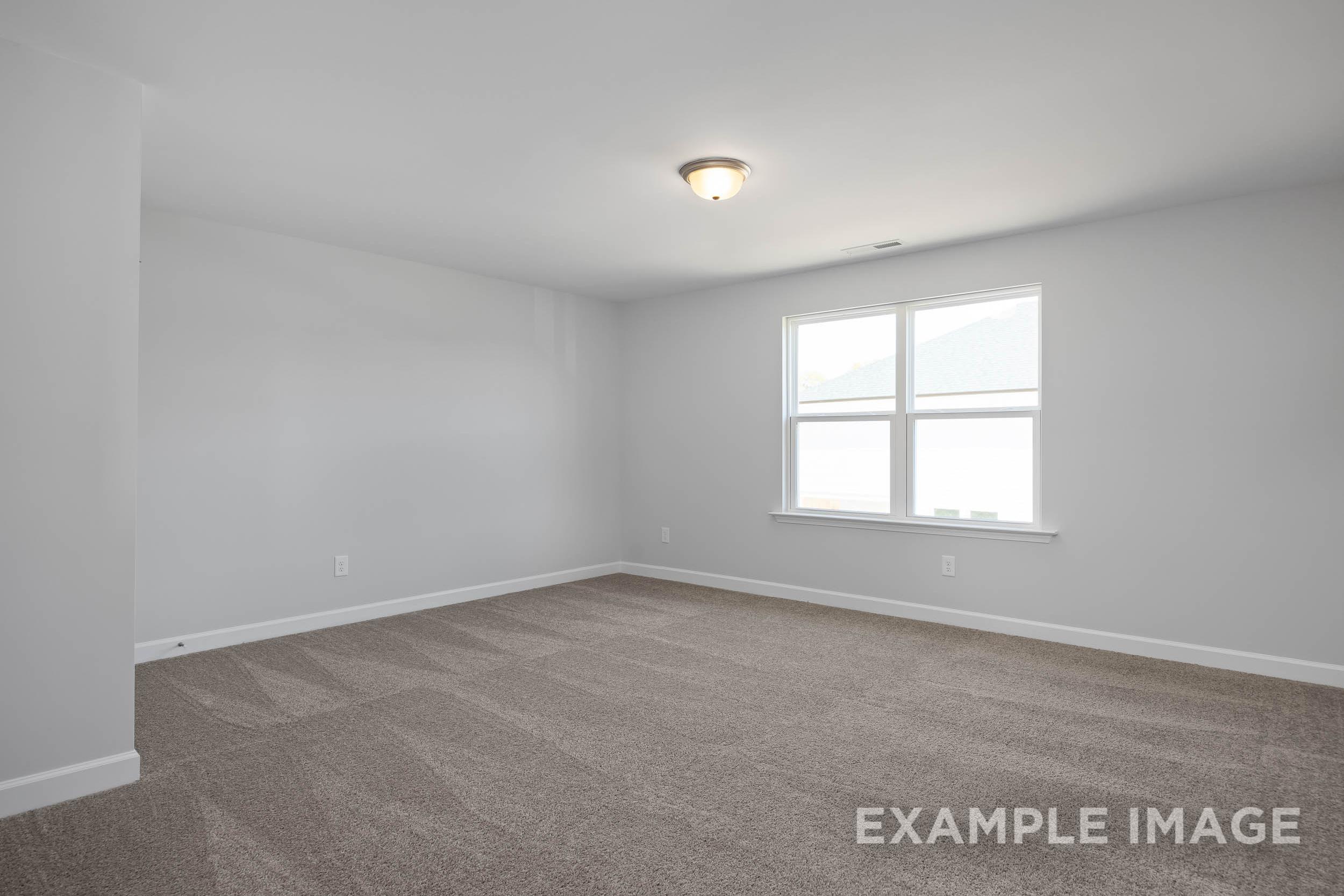 Spacious empty bedroom in The Ash Davidson Homes design with gray walls, beige carpet, and large double windows