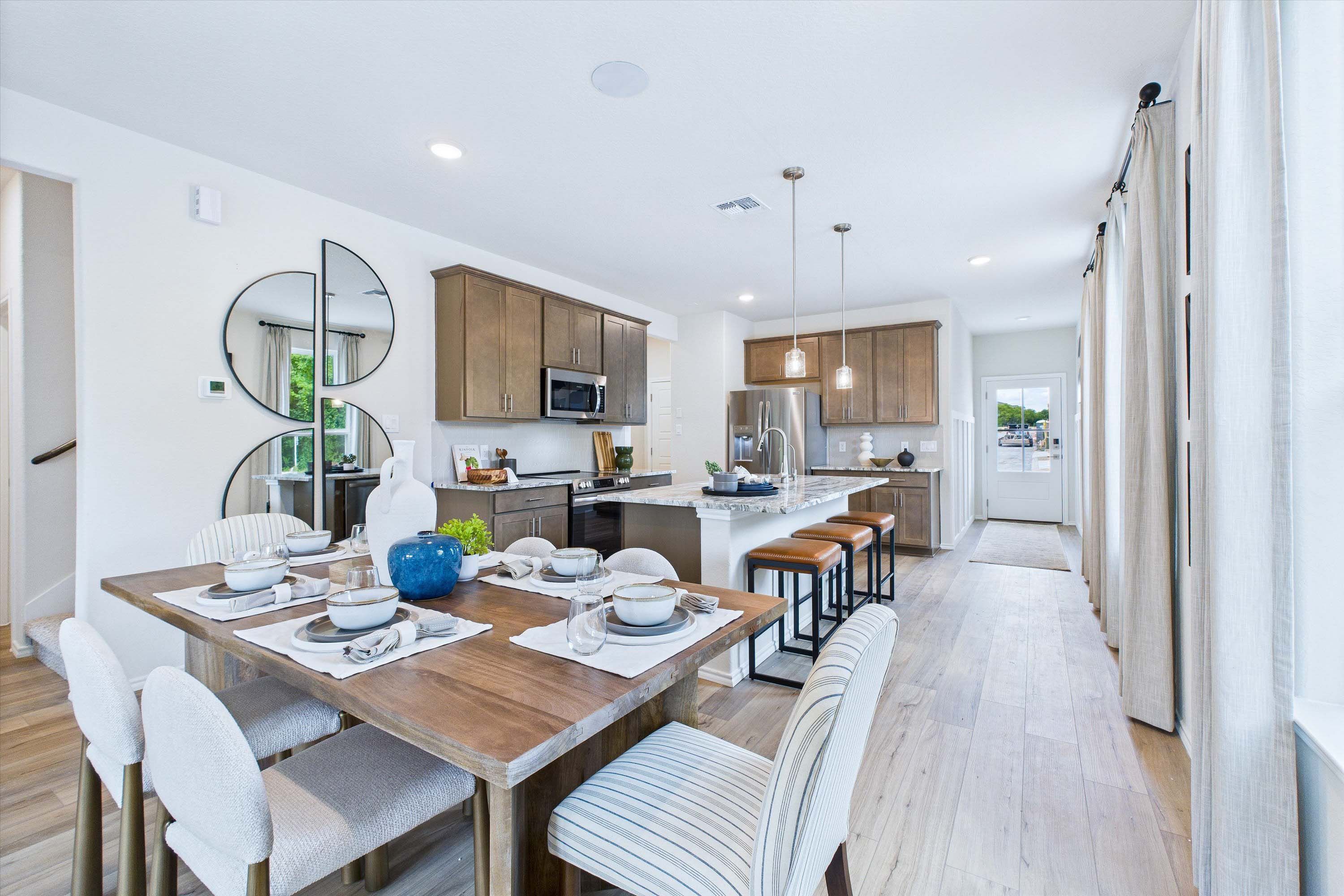 Open-concept dining and kitchen area in The Gillian C home design, featuring a wooden dining table and modern island.