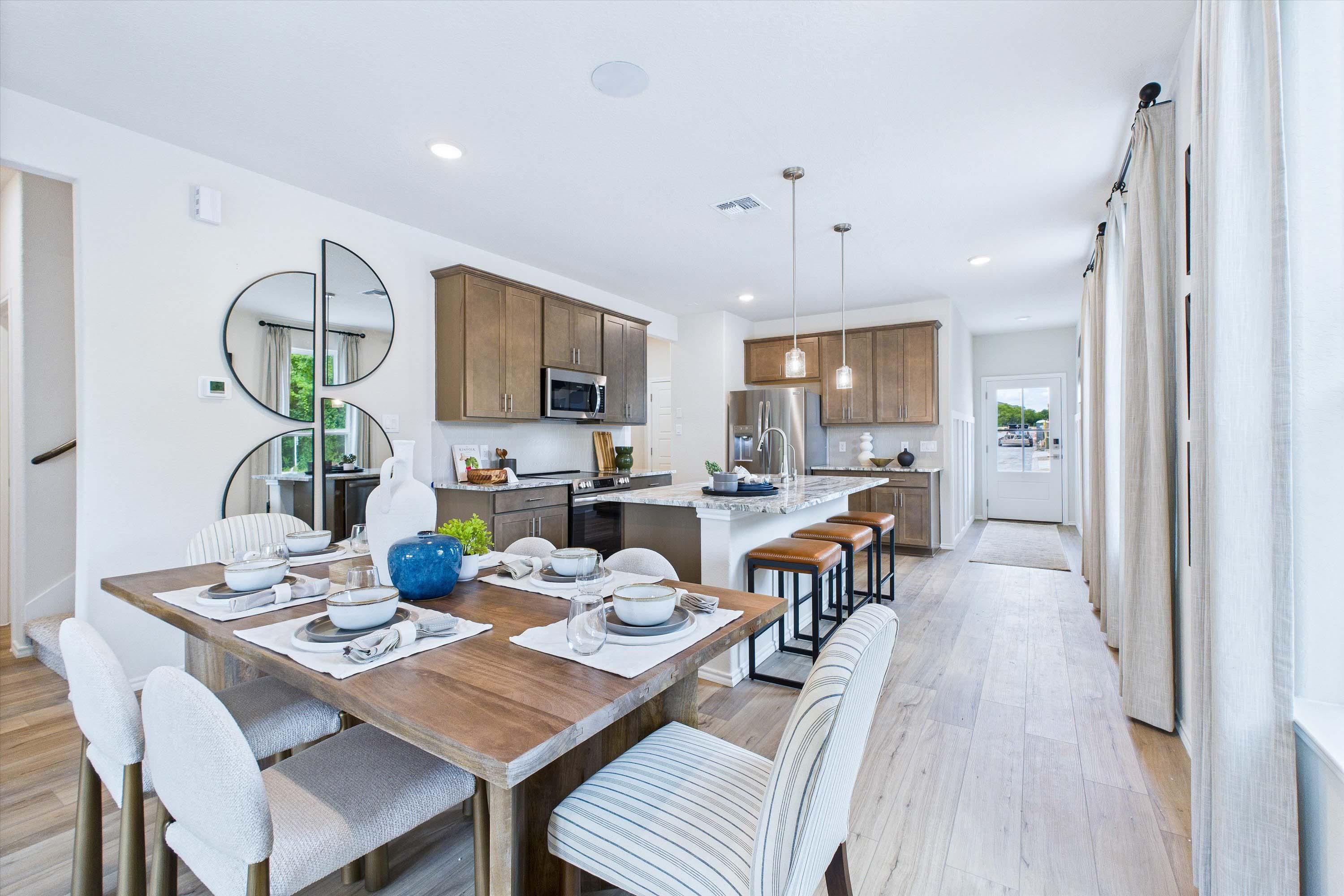 Open-concept dining and kitchen area in The Gillian C home design, featuring a wooden dining table and modern island.