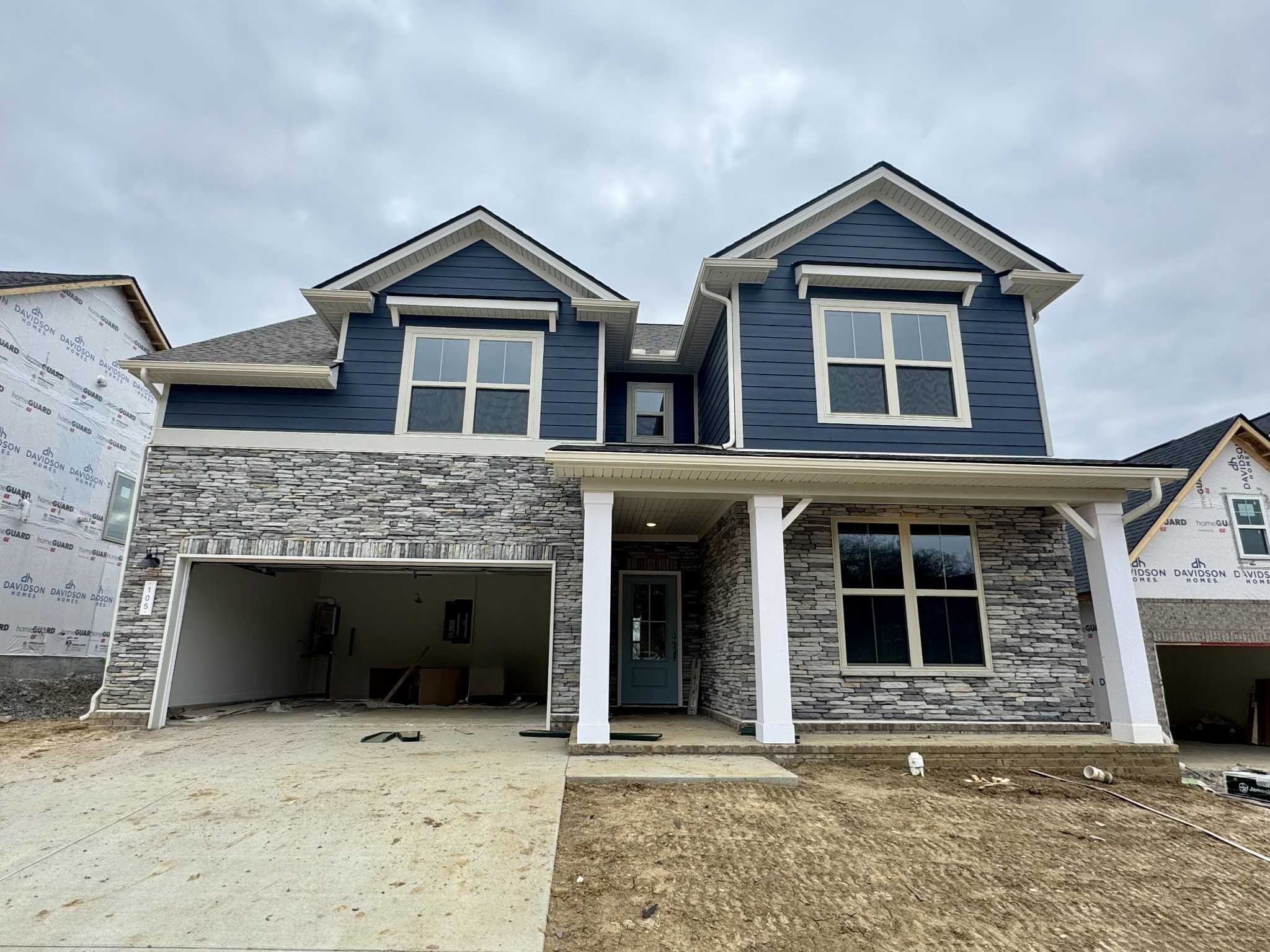 Two-story navy blue home with stone accents, covered porch, columns, and 2-car garage in Woods Crossing, Gallatin, Tennessee