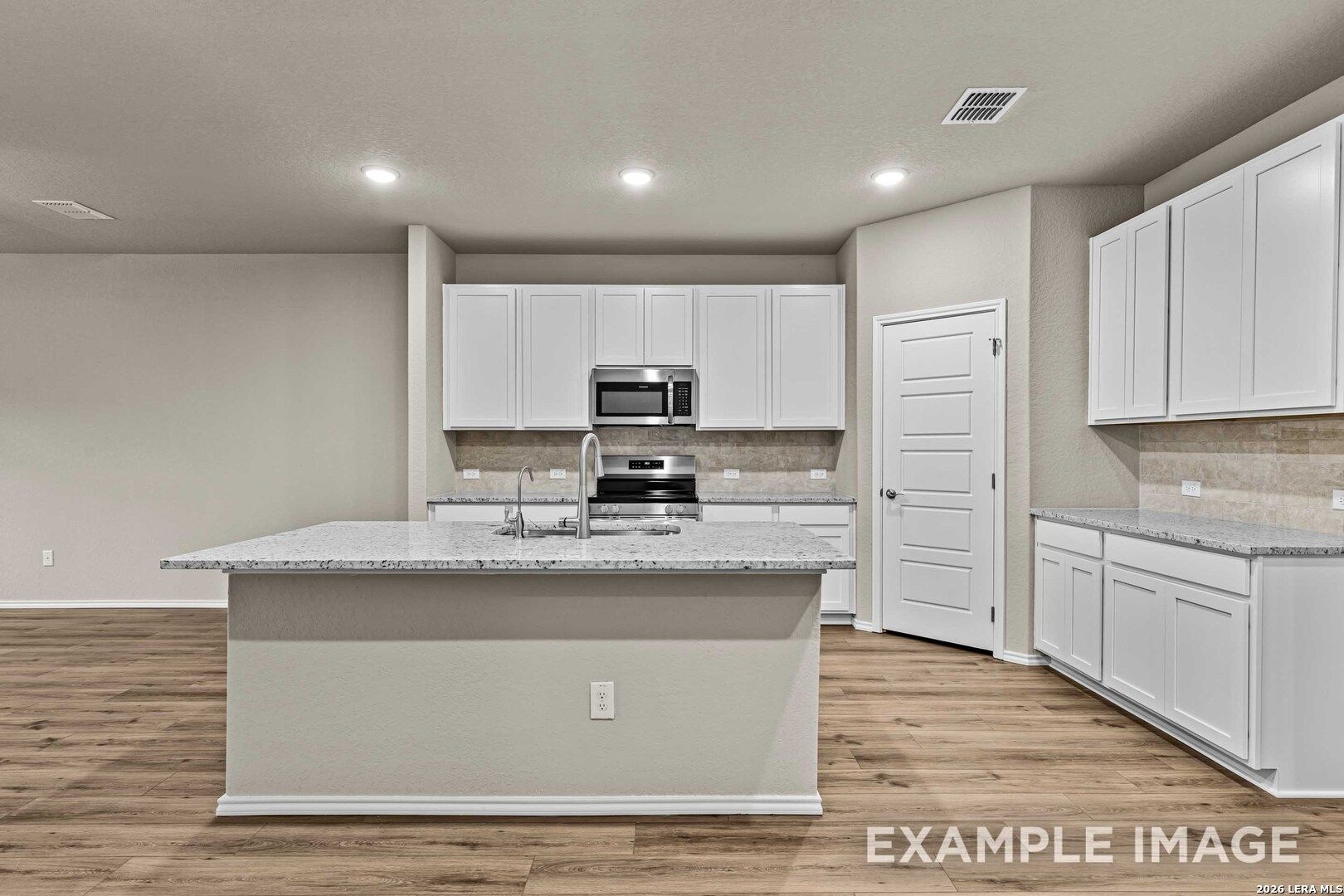Modern kitchen with white cabinets, granite island, and stainless appliances in The Douglas F floor plan, Bricewood, SA.