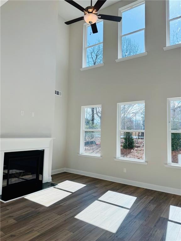 Vaulted ceiling living room with large windows, ceiling fan, white fireplace, hardwood floors in Davidson Homes The Danbury C, Buford GA