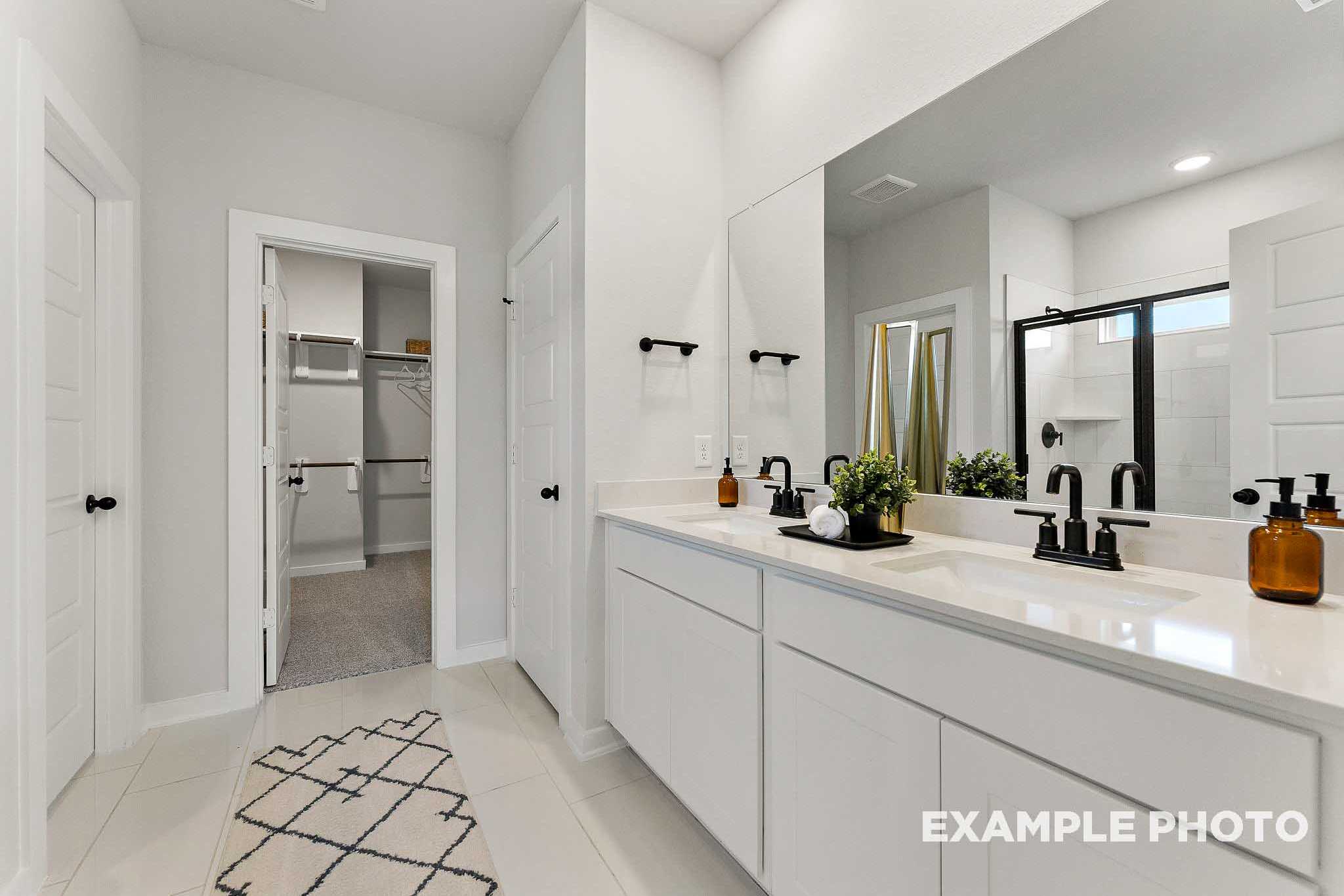 Spacious master bathroom in The Everett E featuring double vanity, white quartz counters, black faucets, and walk-in shower