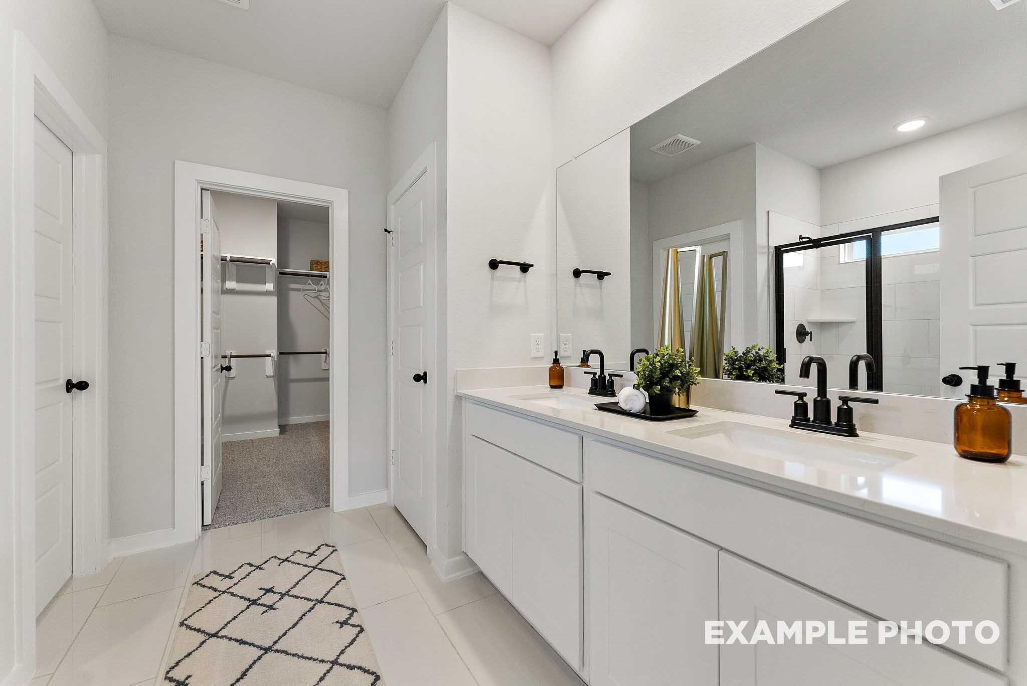 Modern bathroom with dual vanities, white cabinetry, and walk-in closet in The Everett E floor plan, Sundance Cove, Crosby.