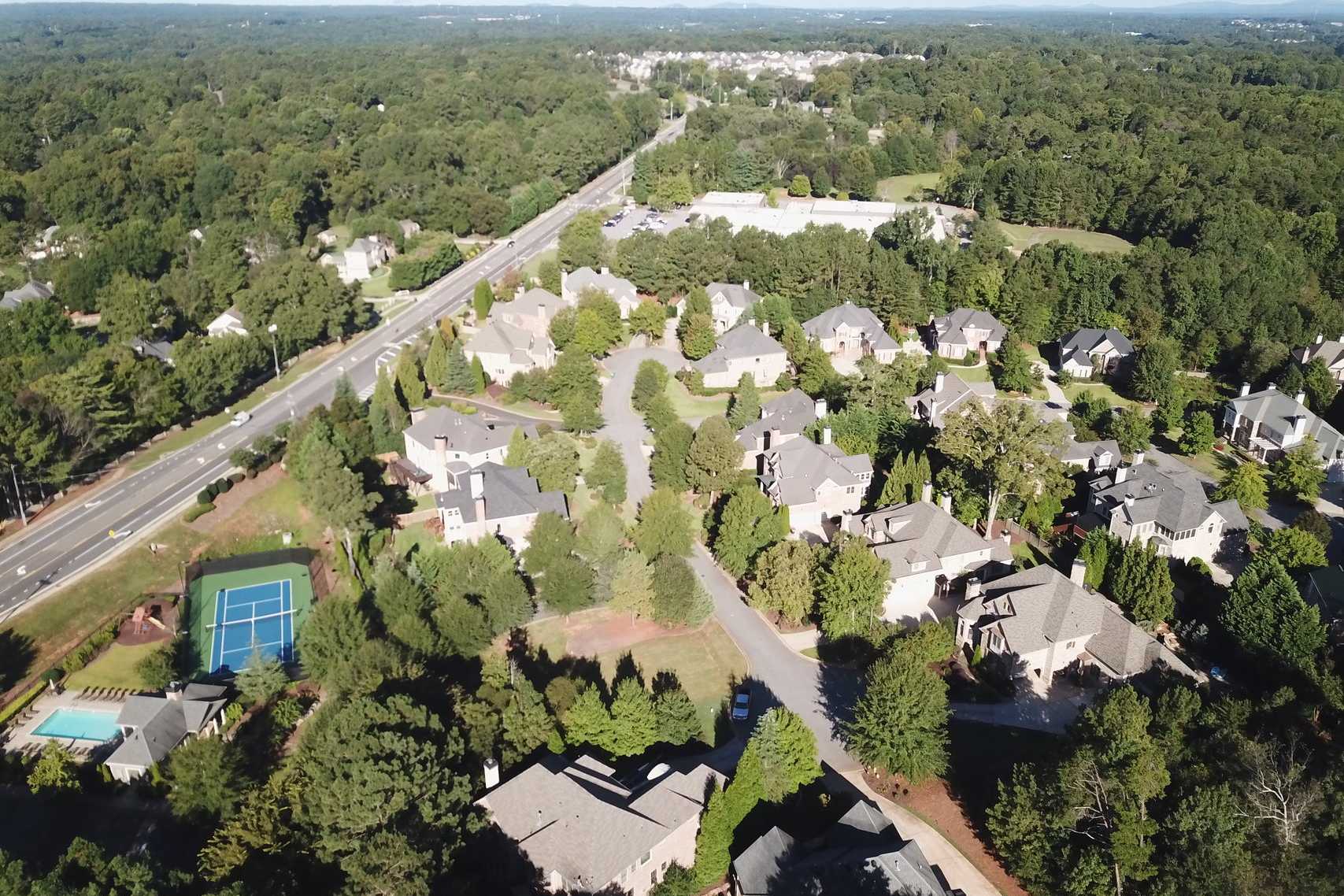 Aerial view of Tanglewood neighborhood in East Cobb Georgia with tree-lined homes pool tennis court and nearby highway by Davidson Homes