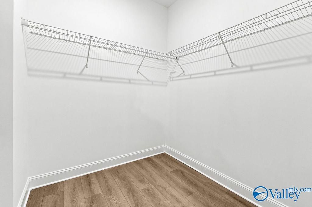 Walk-in closet with white wire shelving and wood-look flooring in The Camilla C home at The Retreat at Cain Park, Hartselle.