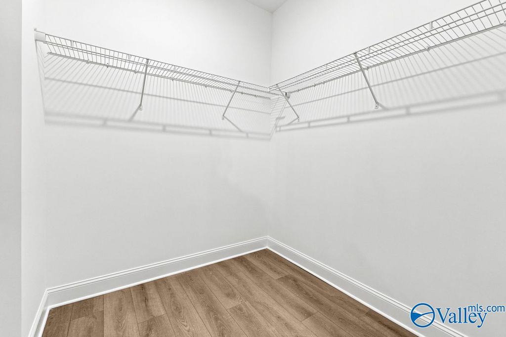 Walk-in closet with white wire shelving and wood-look flooring in The Camilla C home at The Retreat at Cain Park, Hartselle.