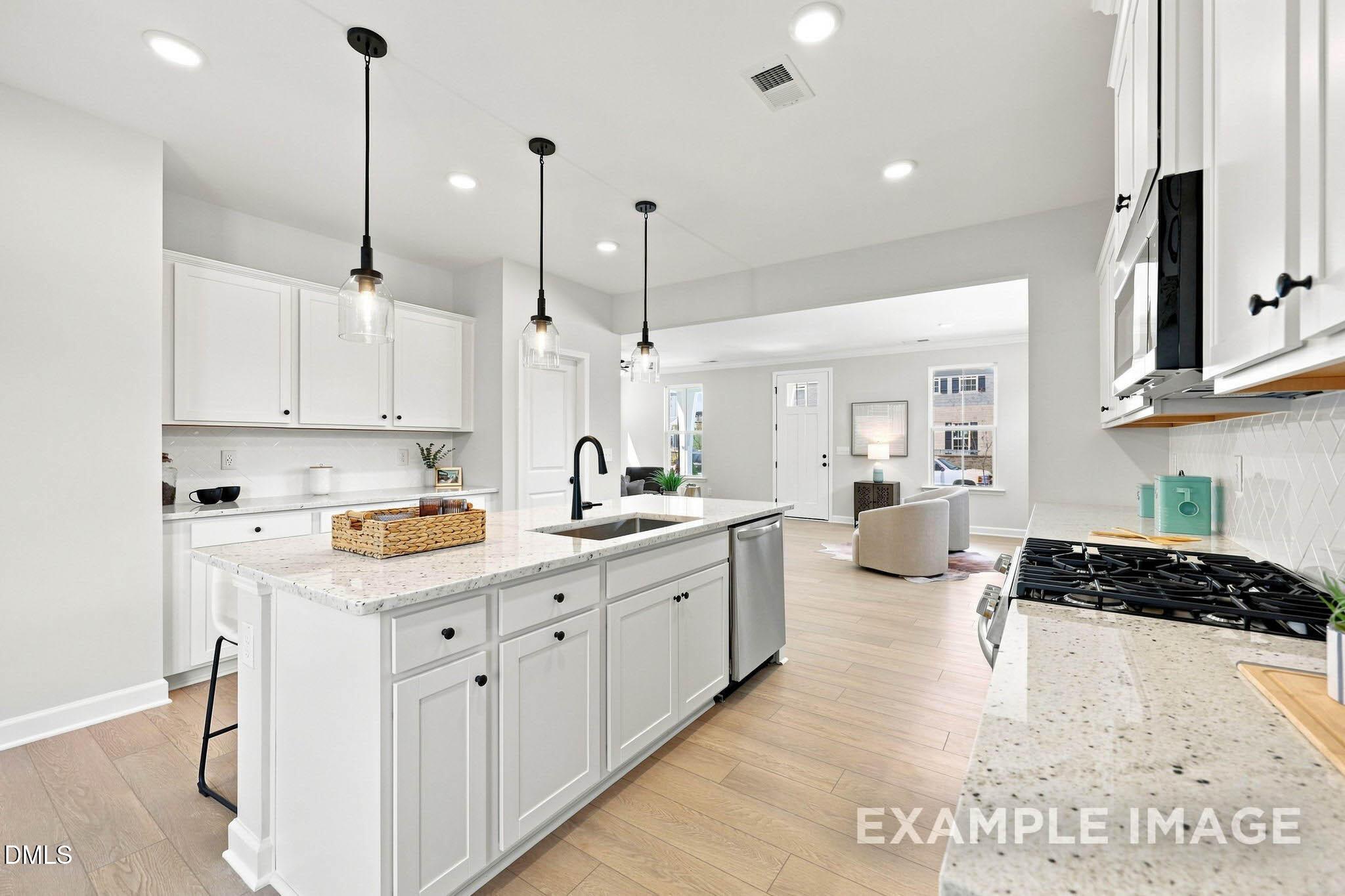 Bright white kitchen with granite island, black pendant lights, and open living area in Davidson Homes The Harris A plan, Knightdale NC